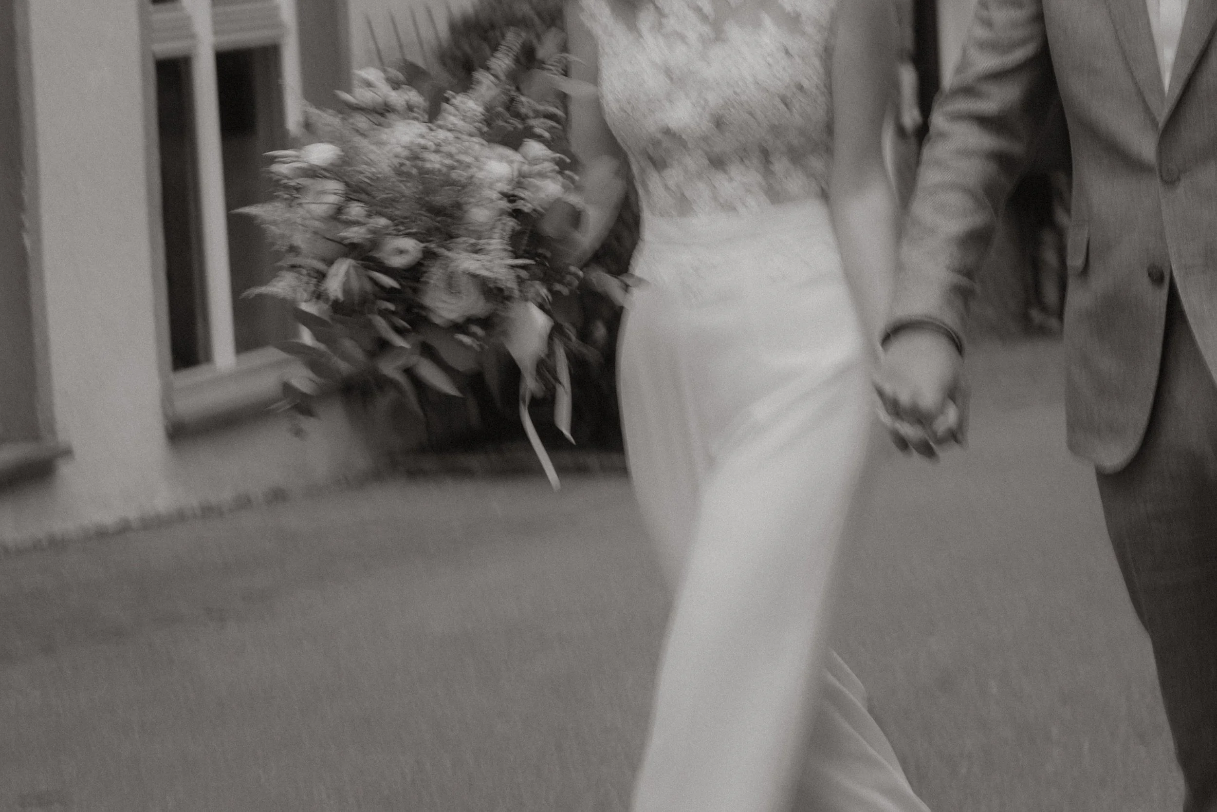 Ein Brautpaar, das Hand in Hand bei einer Hochzeit geht, mit einem Blumenstrauß in der Hand in Rottweil nach ihrer standesamtlichen Hochzeit mit Pia Heim als Hochzeitsfotograf.
