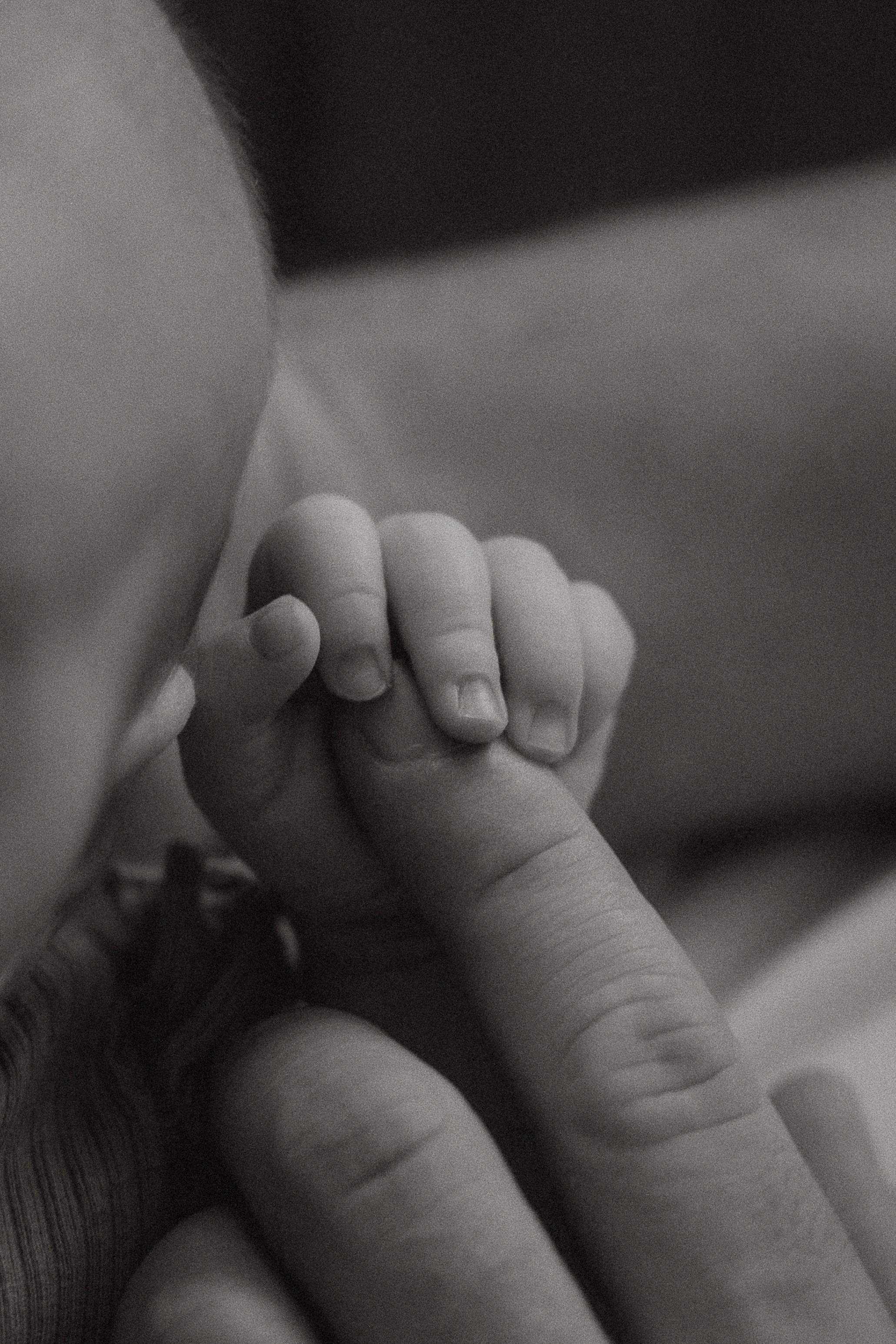 Nahaufnahme eines Erwachsenen, der den Finger eines kleinen Babys hält.