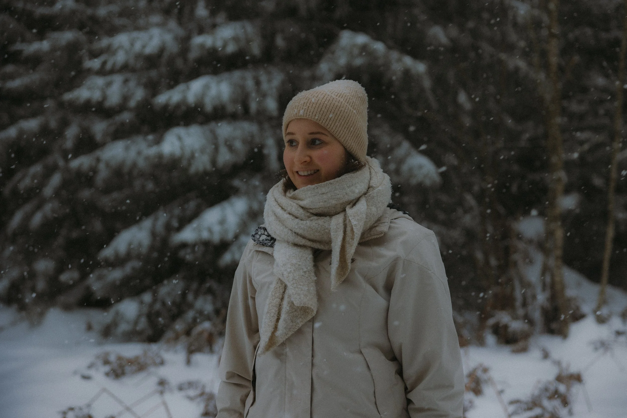Eine lachende Frau bei einem Portraitshooting in Winterkleidung, inklusive Mütze, Schal und Jacke im Schwarzwald im Winter.