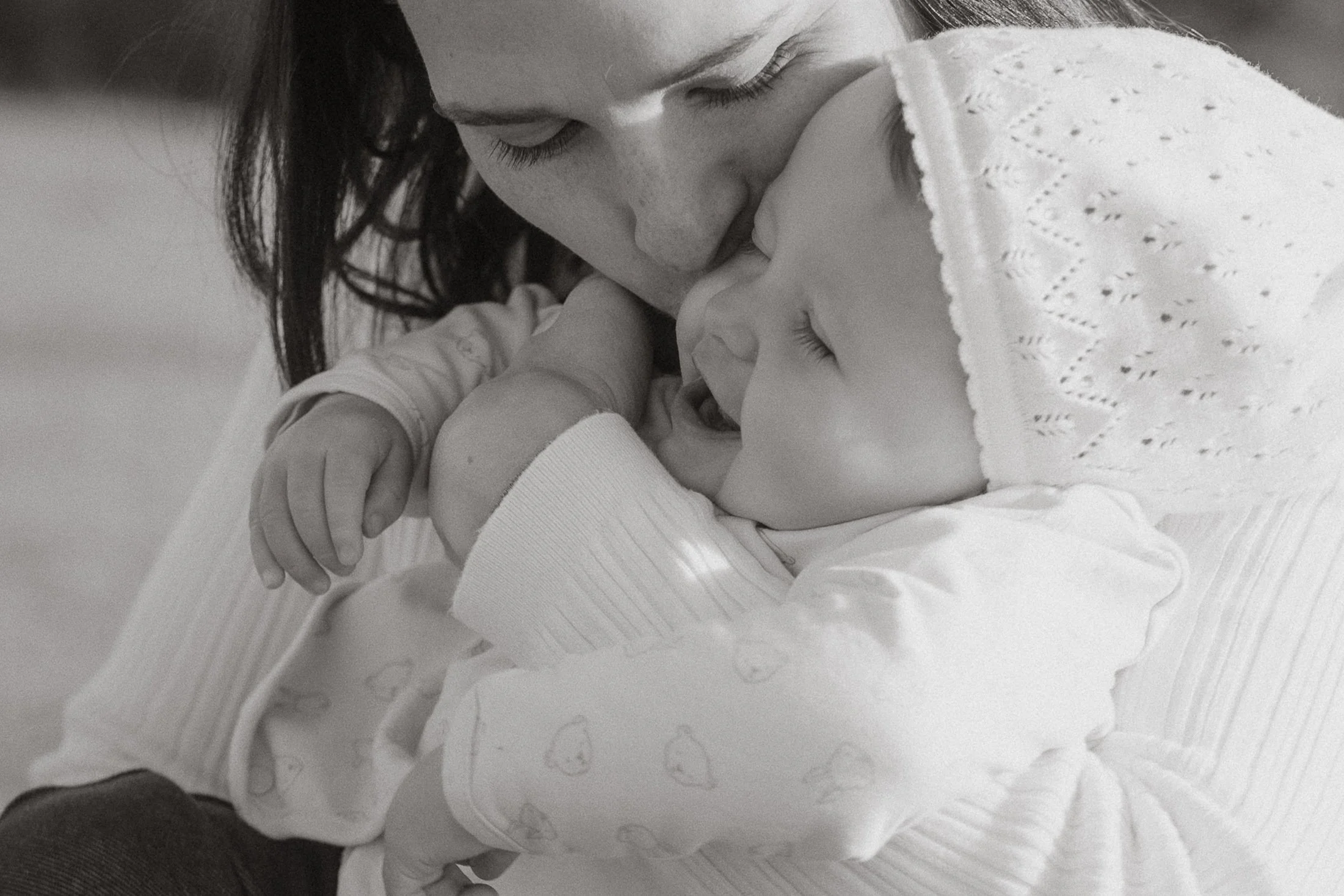 Eine Mama hält ihr lachendes Kind in den Armen und küsst es liebevoll auf die Stirn. Entstanden bei einem Familienshooting mit Pia Lydia Heim.