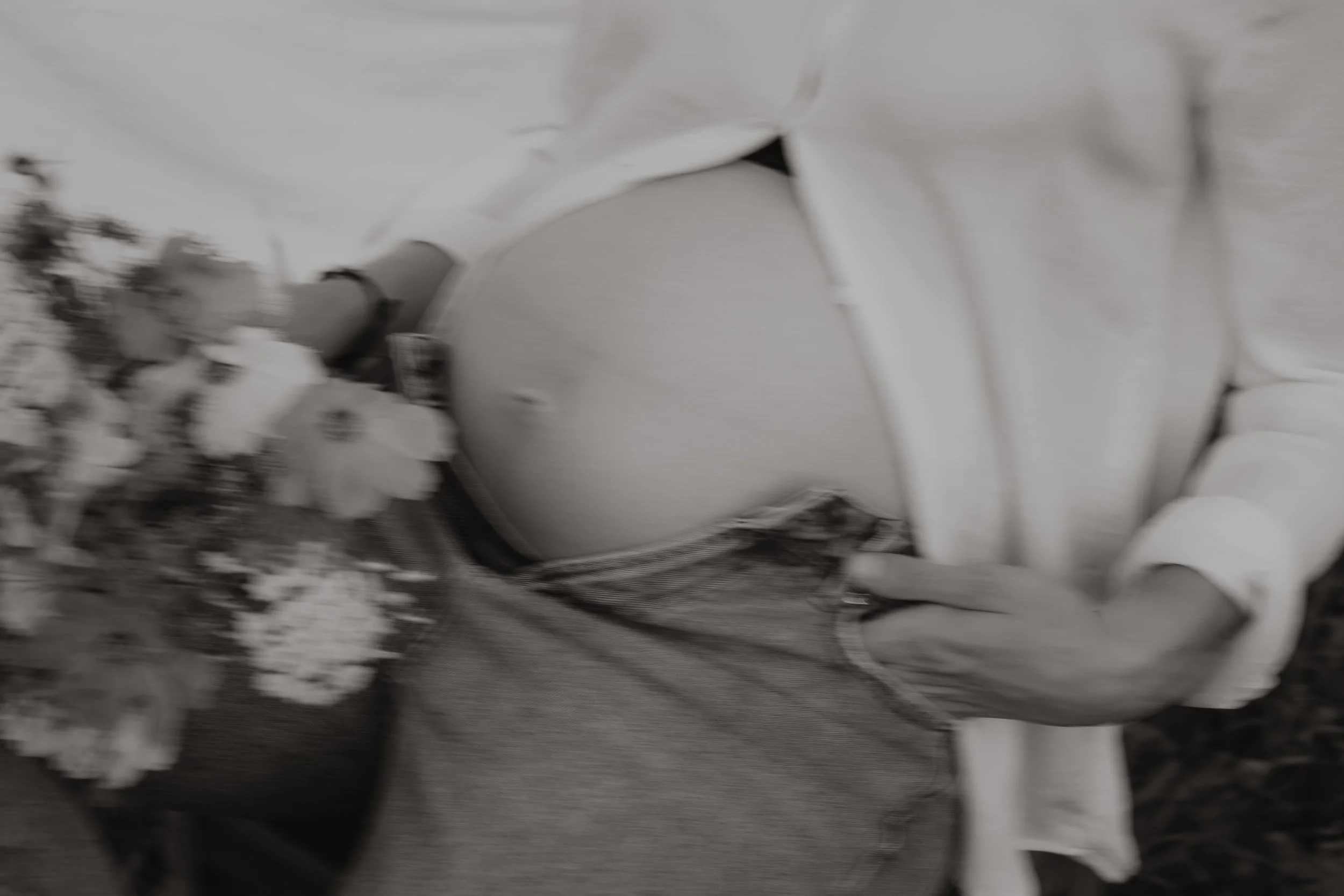 Eine schwangere Frau mit einem weißen Hemd, die Blumen hält und Babybauchbilder mit Fotografin Pia Heim macht.