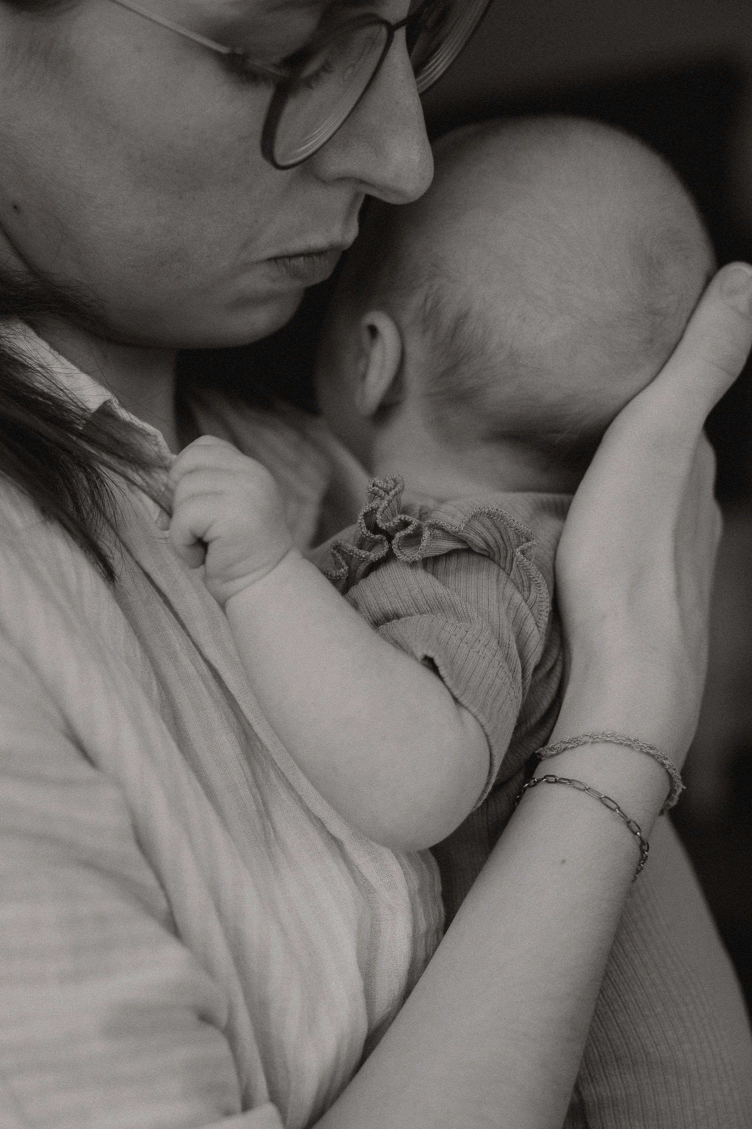 Eine Frau hält ein schlafendes Baby an ihrer Schulter, beide zu sehen in einer Nahaufnahme in Schwarz-Weiß.