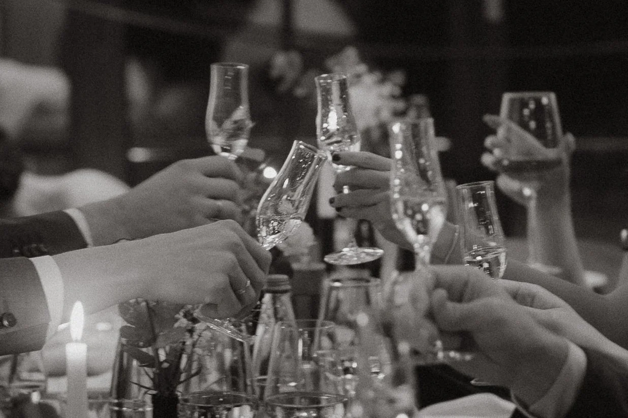 Menschen stoßen mit Champagnergläsern bei einer Hochzeit an.