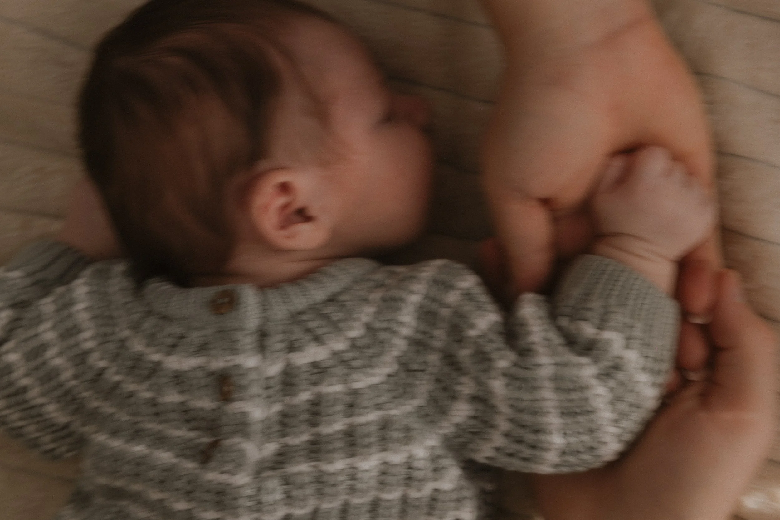 Ein kleines Baby, das in den Armen gehalten wird, liegt auf dem Boden und schläft.