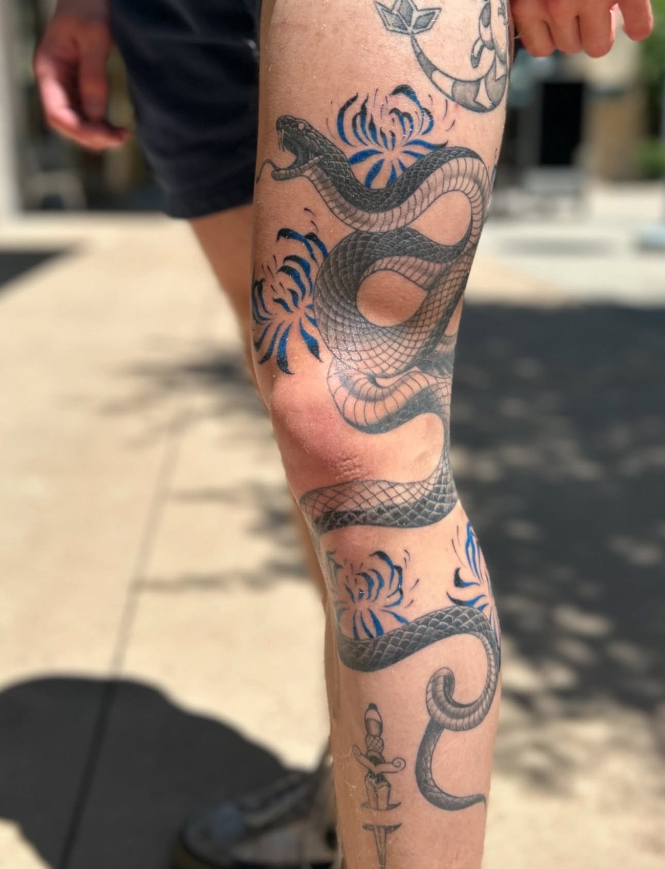 Tattoo of a snake with blue accents on a person's lower leg.