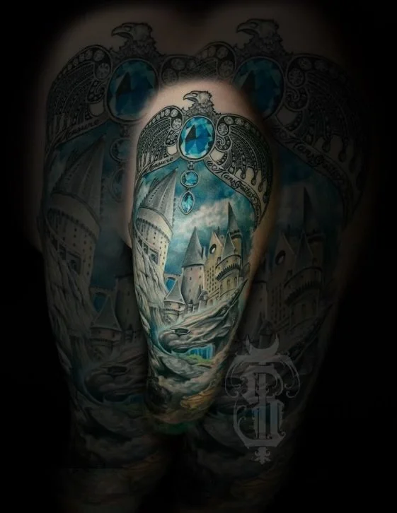 Tattoo of a castle and landscape with blue gemstones on a person's back.