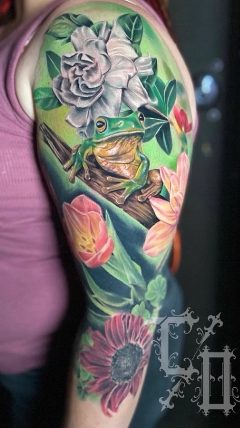 Colorful tattoo of a frog sitting on a branch 