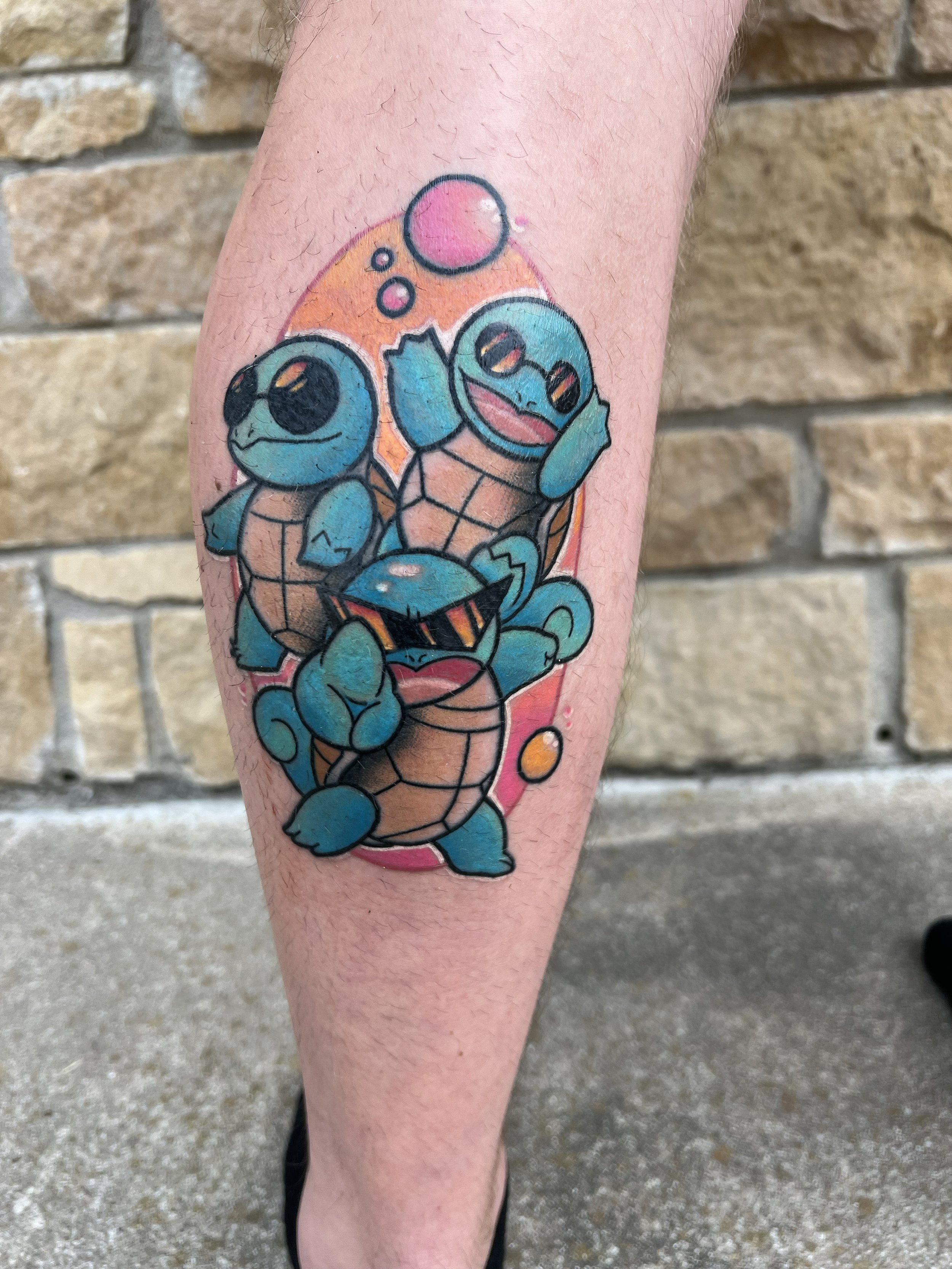 a photo taken outside of a colorful tattoo of 3 charizard pokemon characters in different positions on someone's outer calf