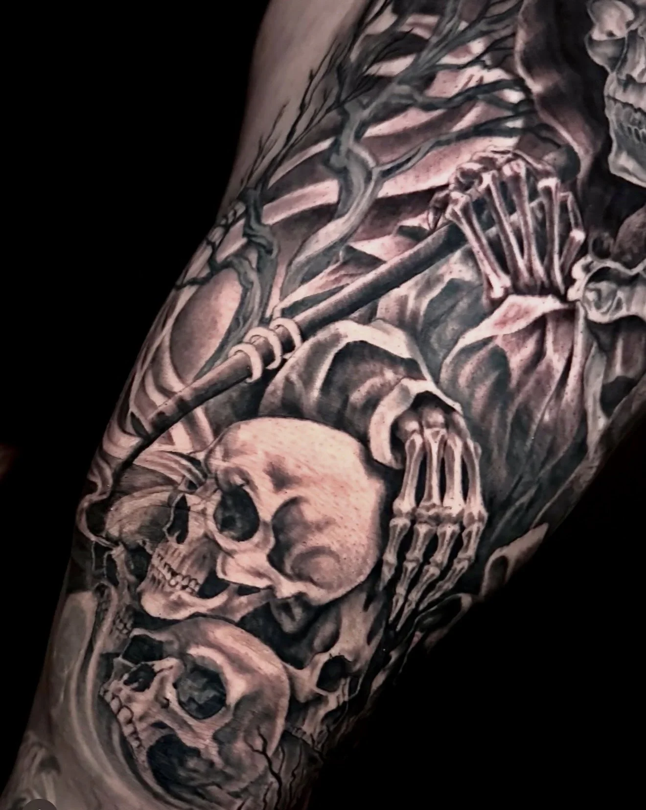 Tattoo of a skeleton, skull, and bones covering an arm.