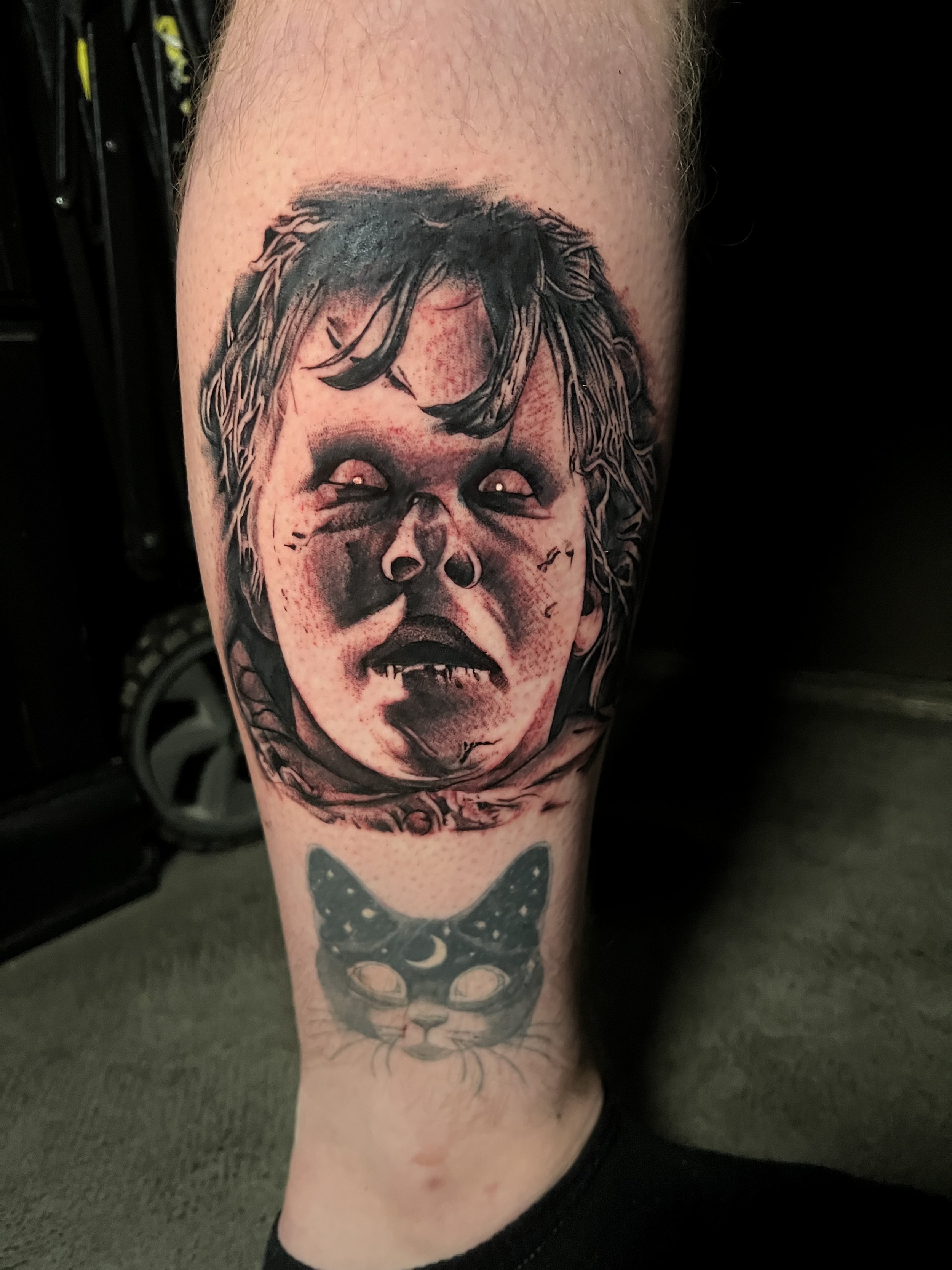 Tattoo of a child's face with bunny ears wearing a bowtie on a person's leg.
