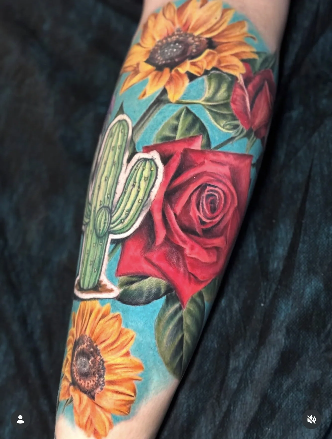 Colorful tattoo sleeve featuring a sunflower at the top, a red rose in the middle, a green cactus on the left, and a sunflower at the bottom, all on a person's arm.