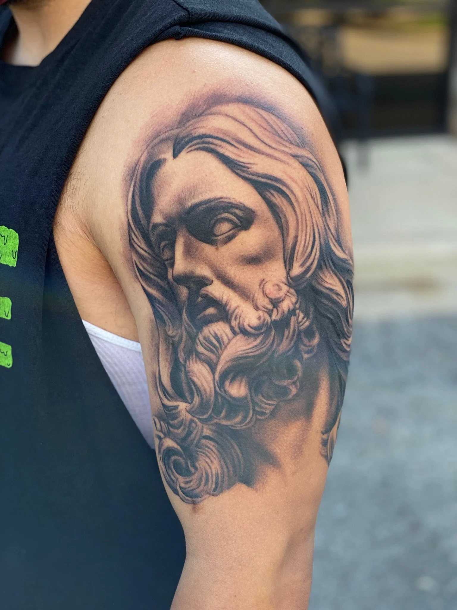 Tattoo of a bearded man with long hair on upper arm.
