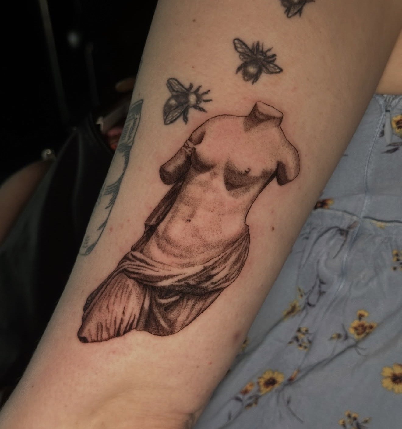Tattoo of a meat cut on a person's arm, surrounded by tattooed bees.