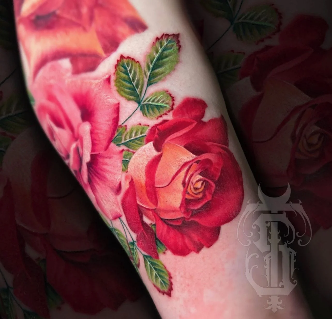 Tattoo of a detailed red and pink rose with green leaves on a person's arm.
