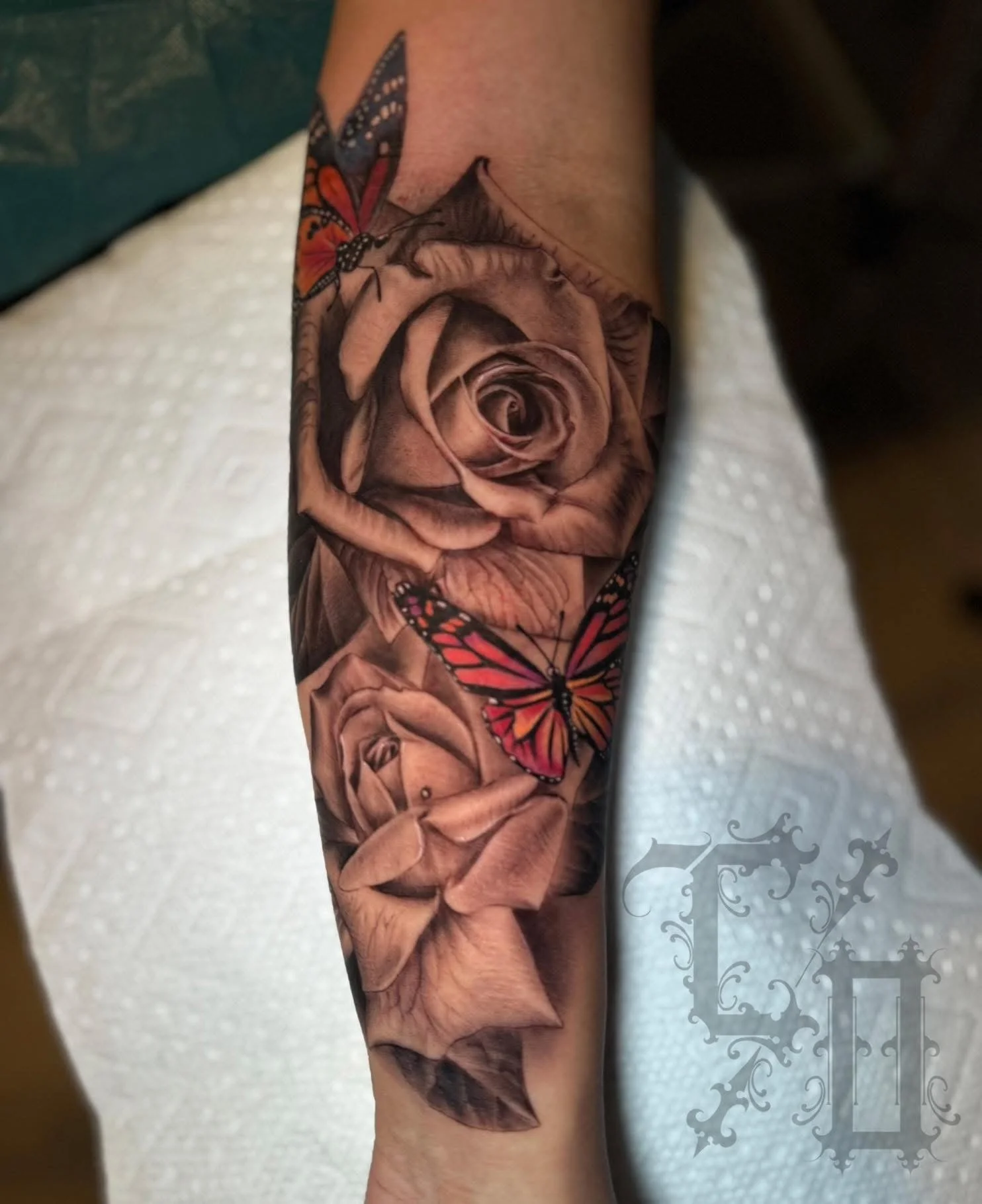 Realistic black and gray tattoo of a rose and butterflies on a person's forearm.