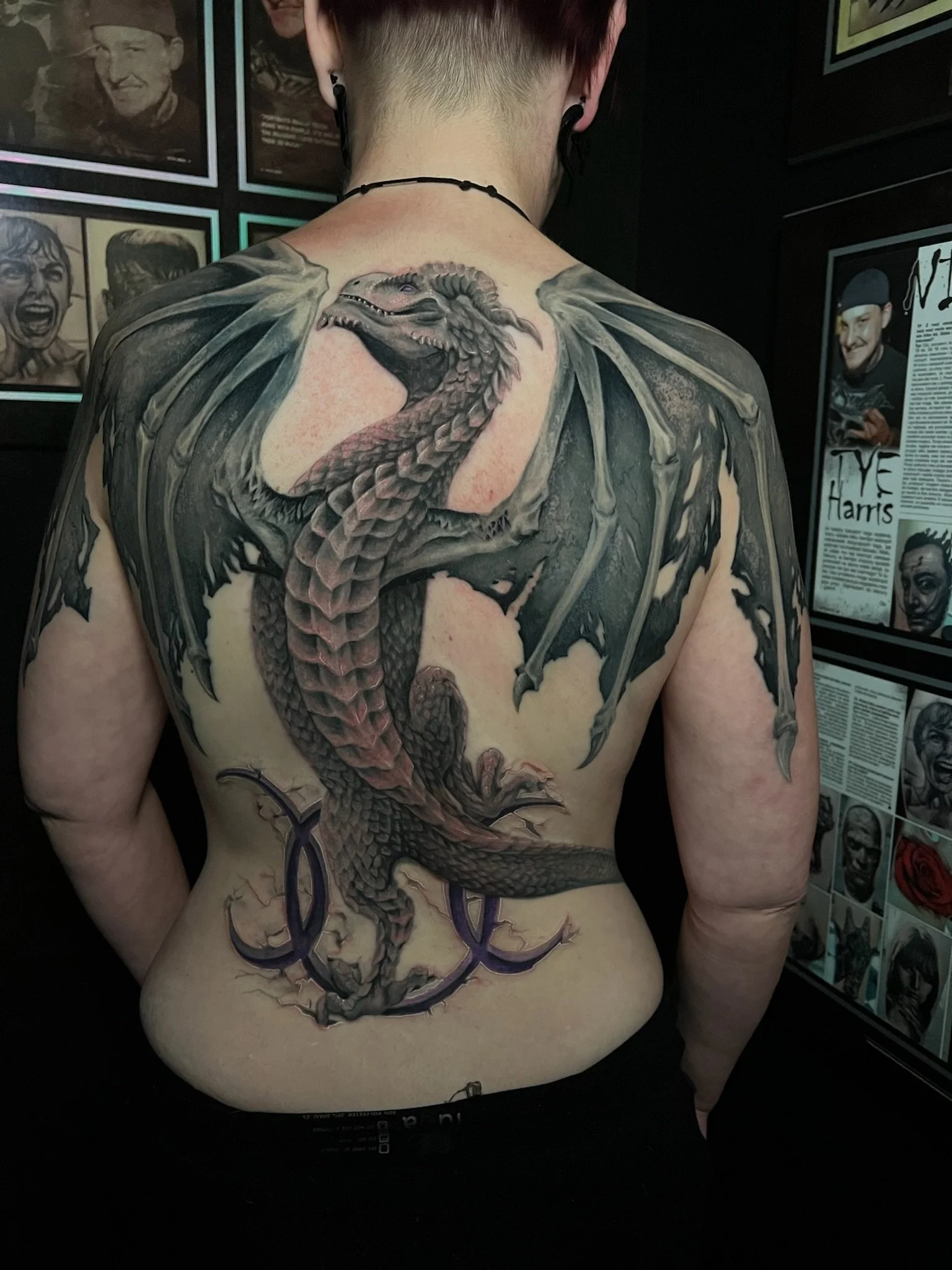 Back tattoo of a dragon with outstretched wings and a menacing expression.