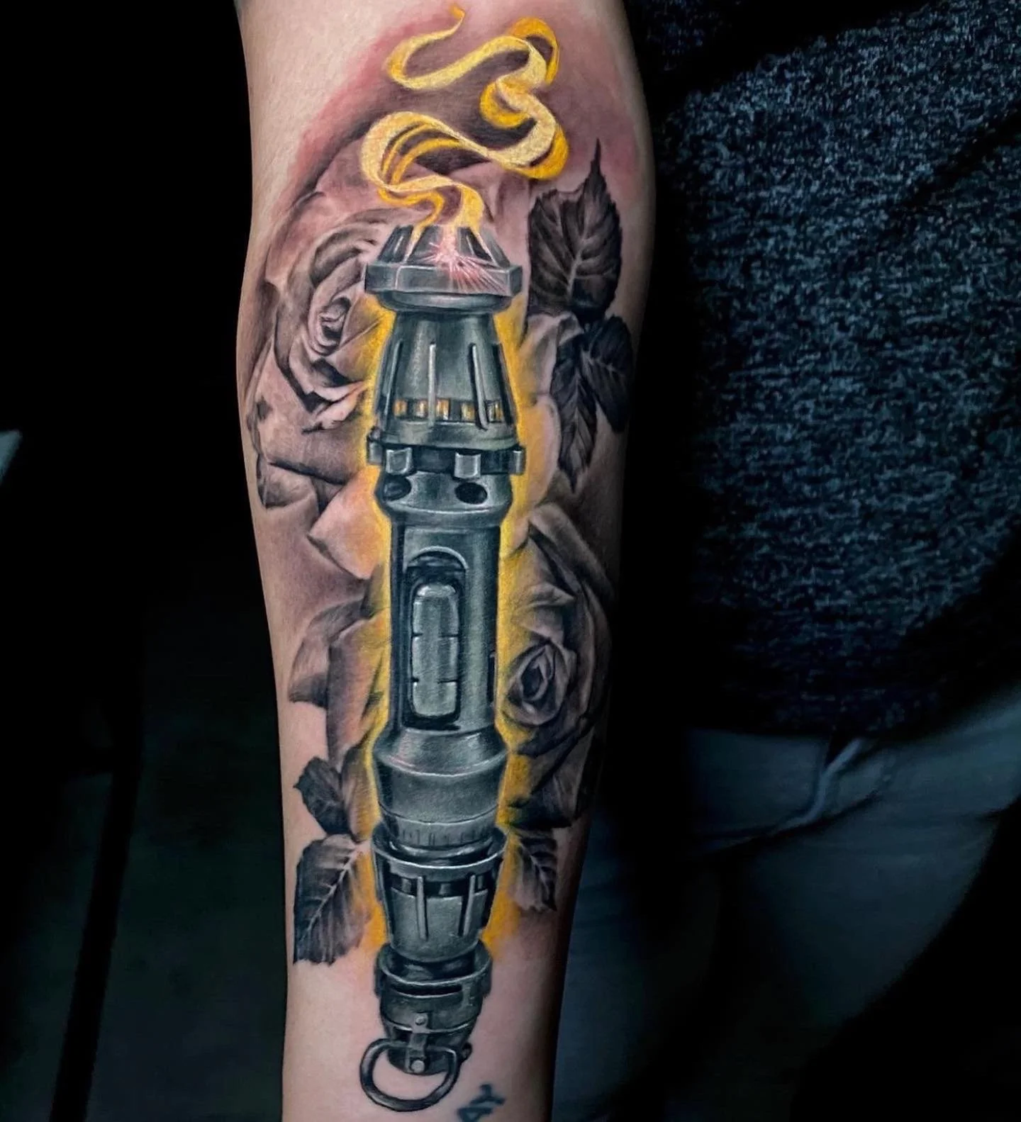 Tattoo of a grenade with roses and leaves in the background on a person's arm.