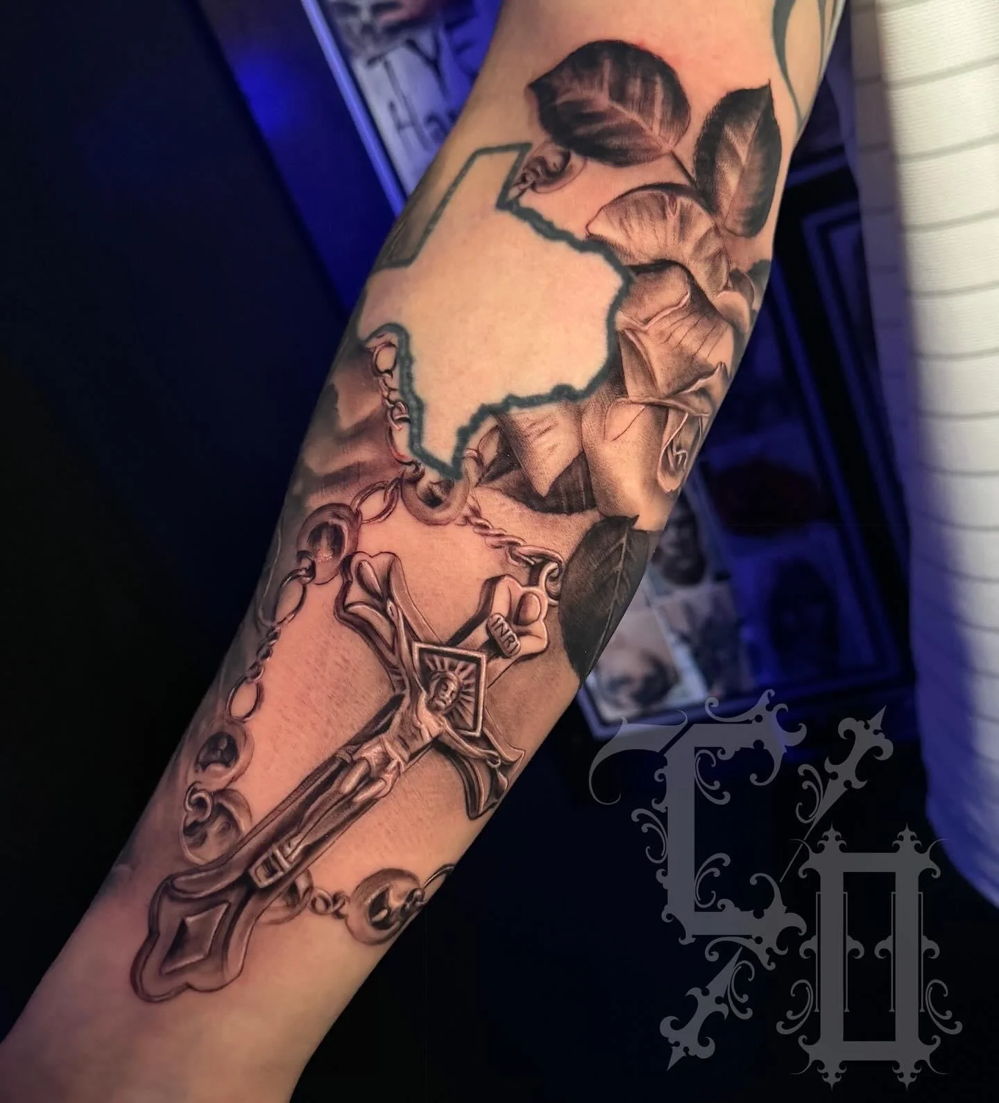 Tattoo of the state of Texas with a rose design, a rosary with a crucifix, and artistic shading in black and gray.