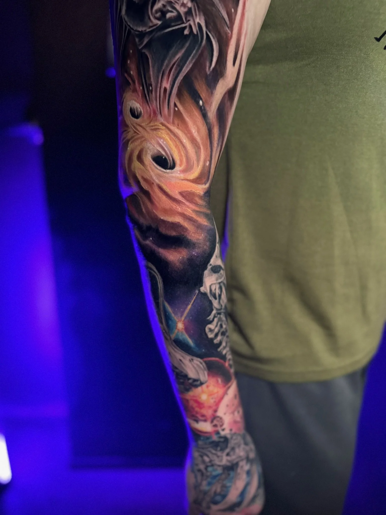 Colorful sleeve tattoo featuring a lion's face and a cosmic scene with stars and nebulae.