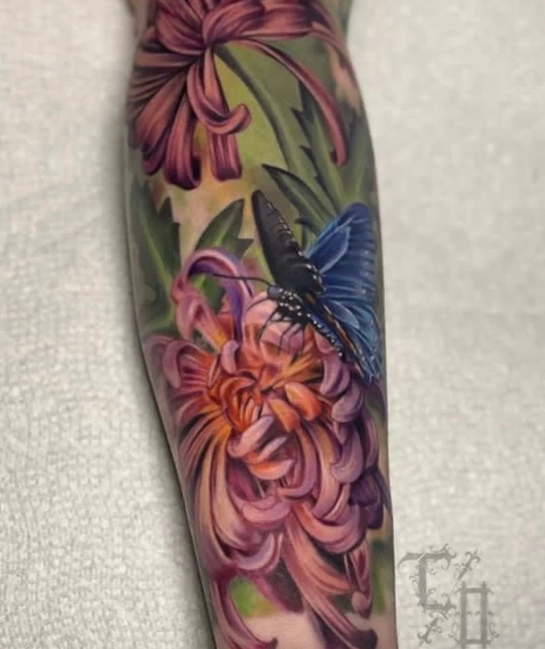 Tattoo of a butterfly on a colorful flower background on a person's arm.