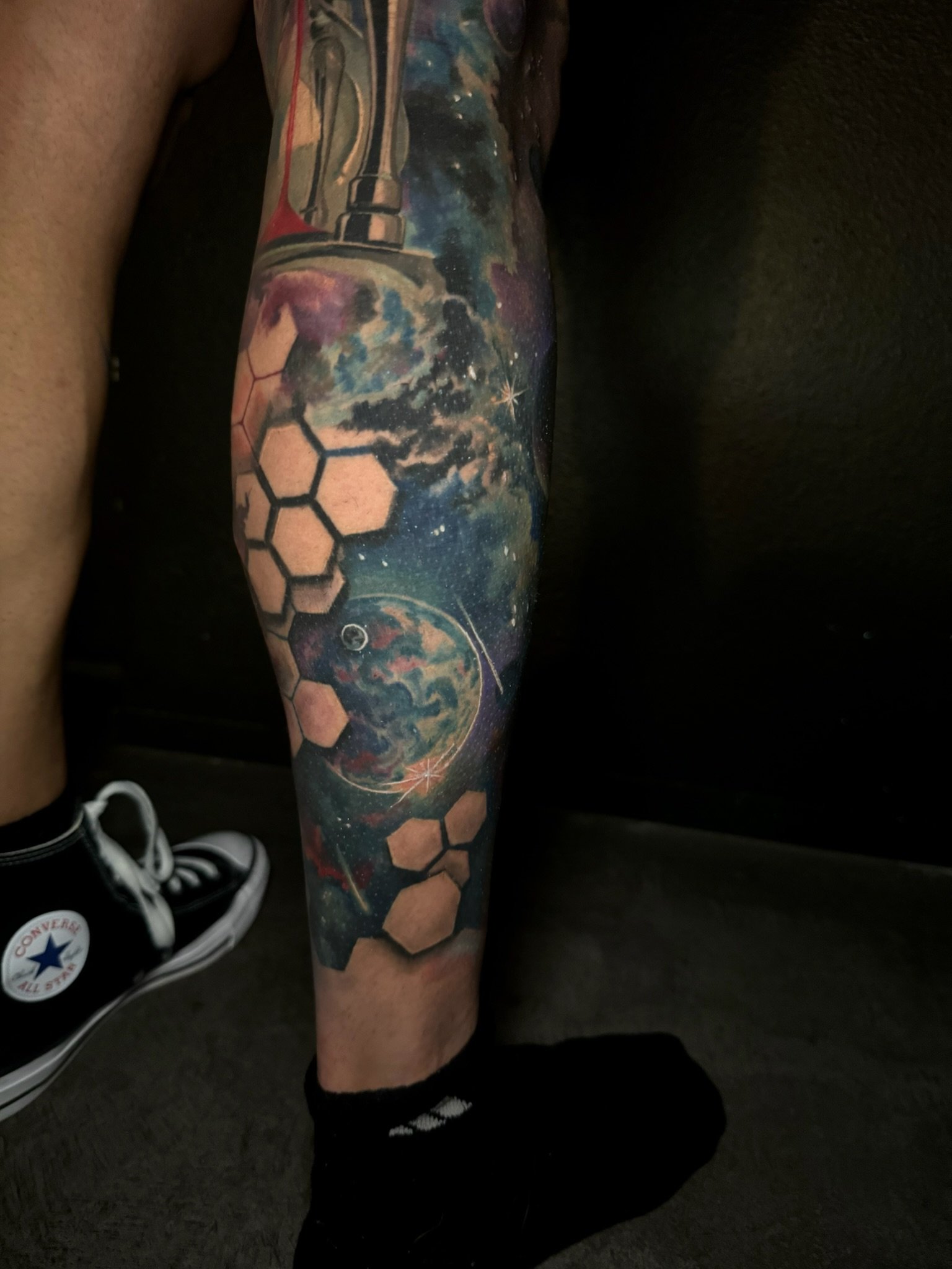 Tattoo sleeve featuring celestial and space themes, including planets, stars, and honeycomb patterns on a person's arm.
