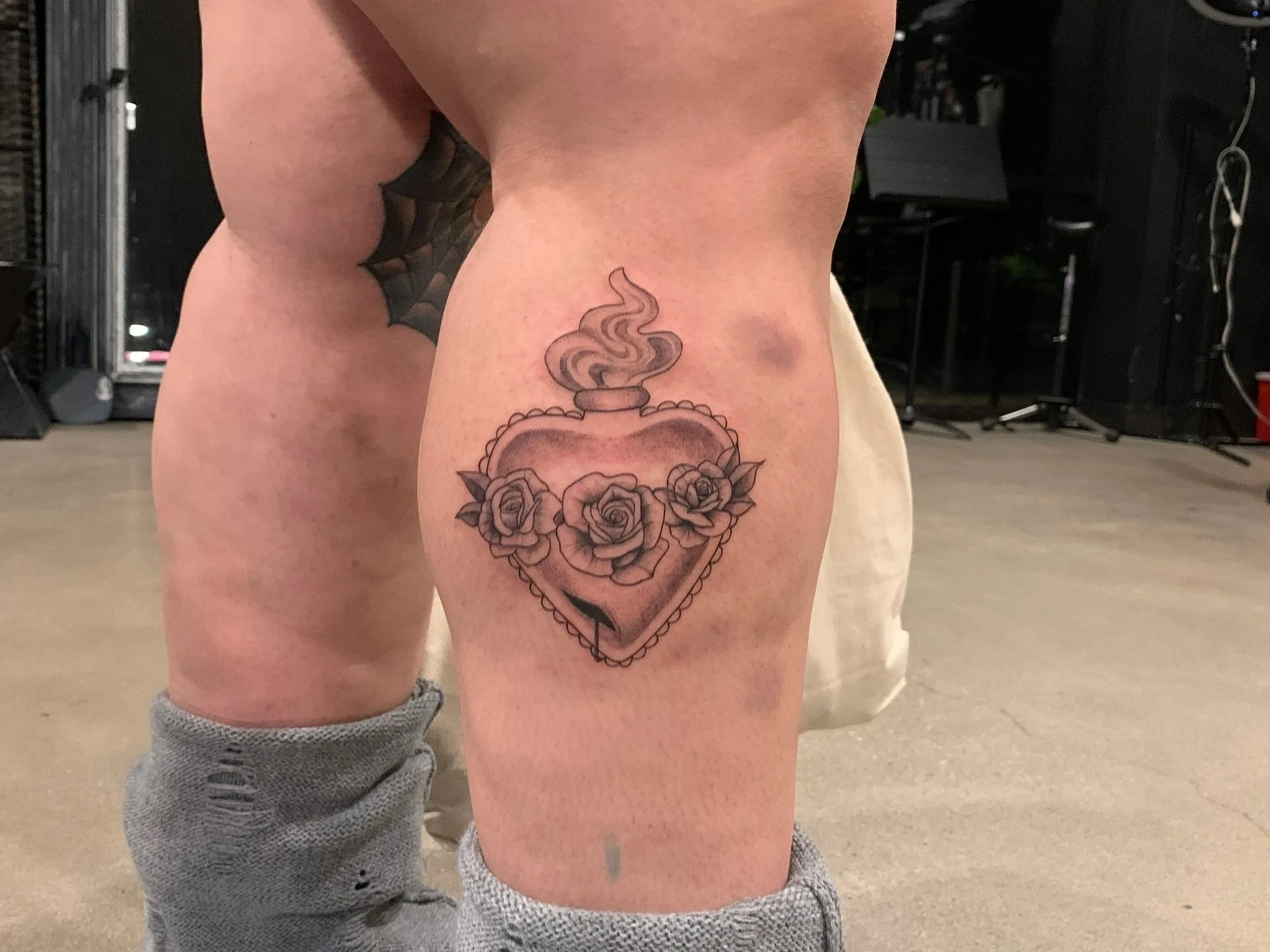 Tattoo of a steaming cup with roses around it on a person's thigh.