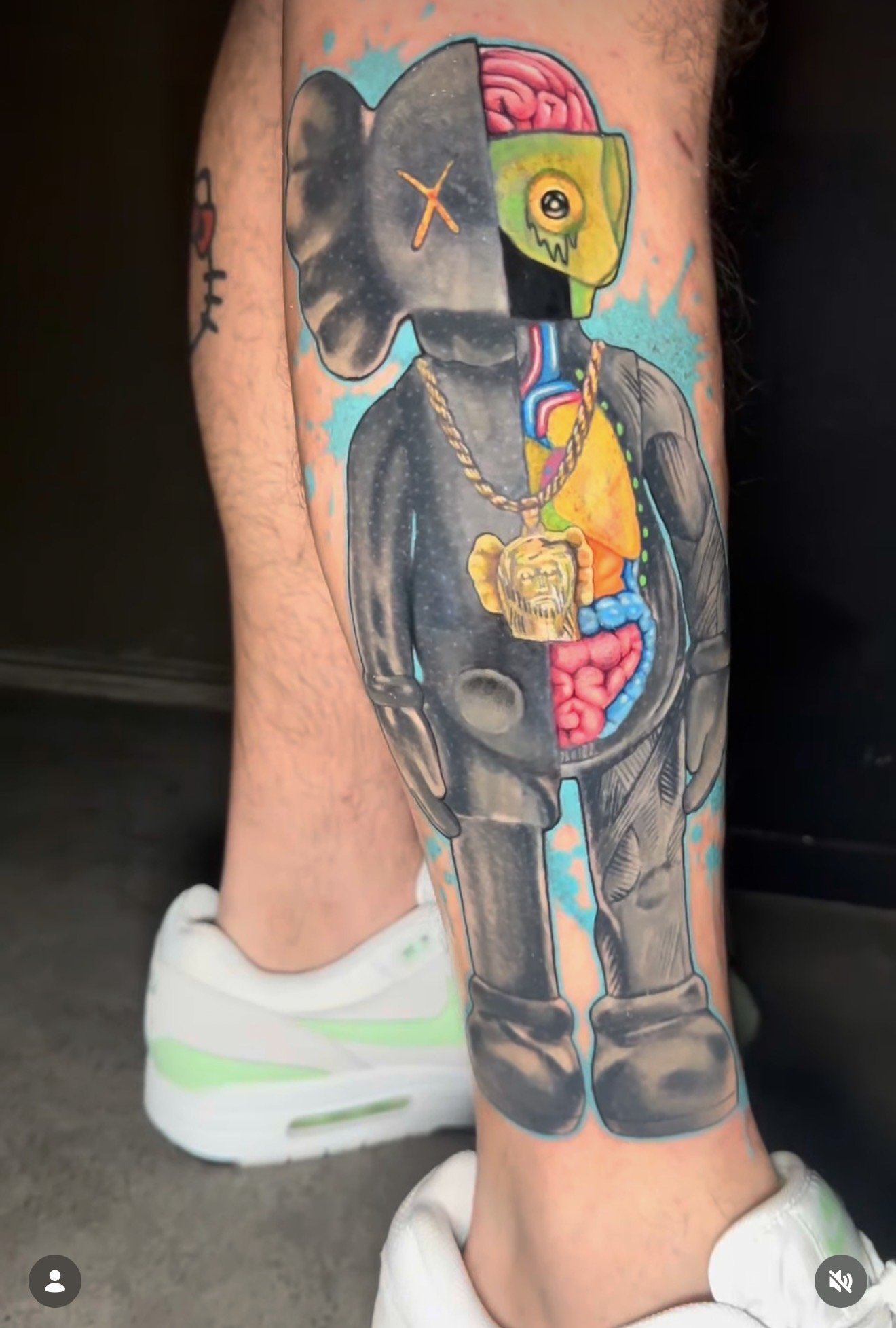 Tattoo of a space-themed design on a person's arm, featuring a gun with an anatomical brain, a clock for a face, colorful internal organs, and a yellow skull with a single eye and black markings.