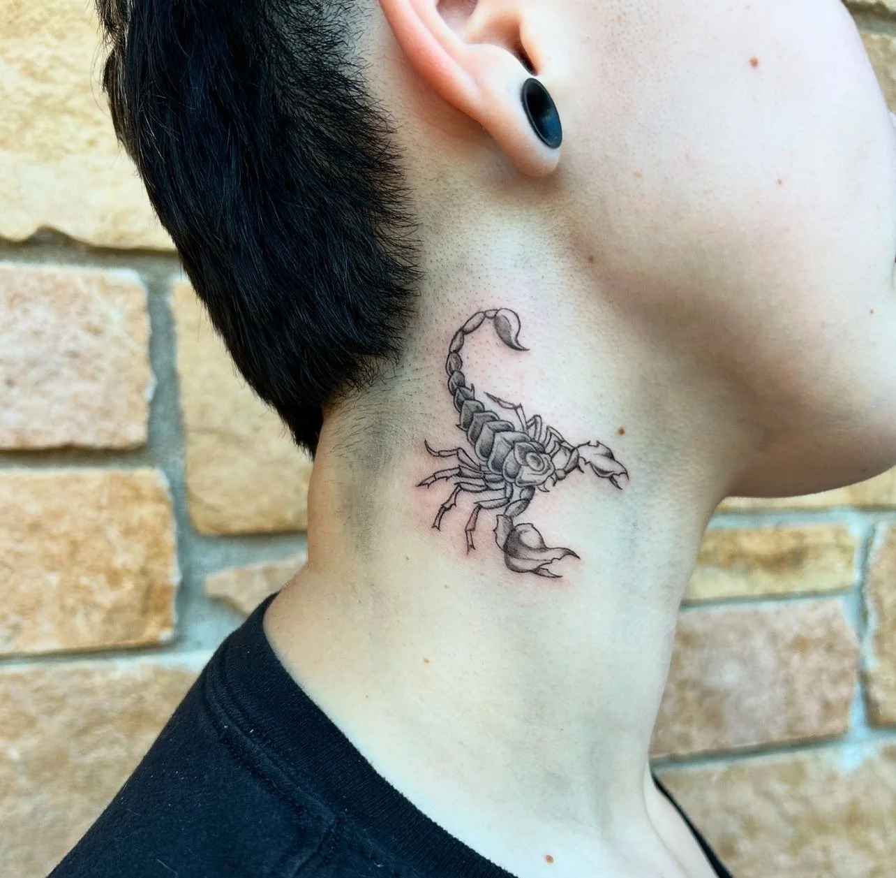 Tattoo of a scorpion on the person's neck.