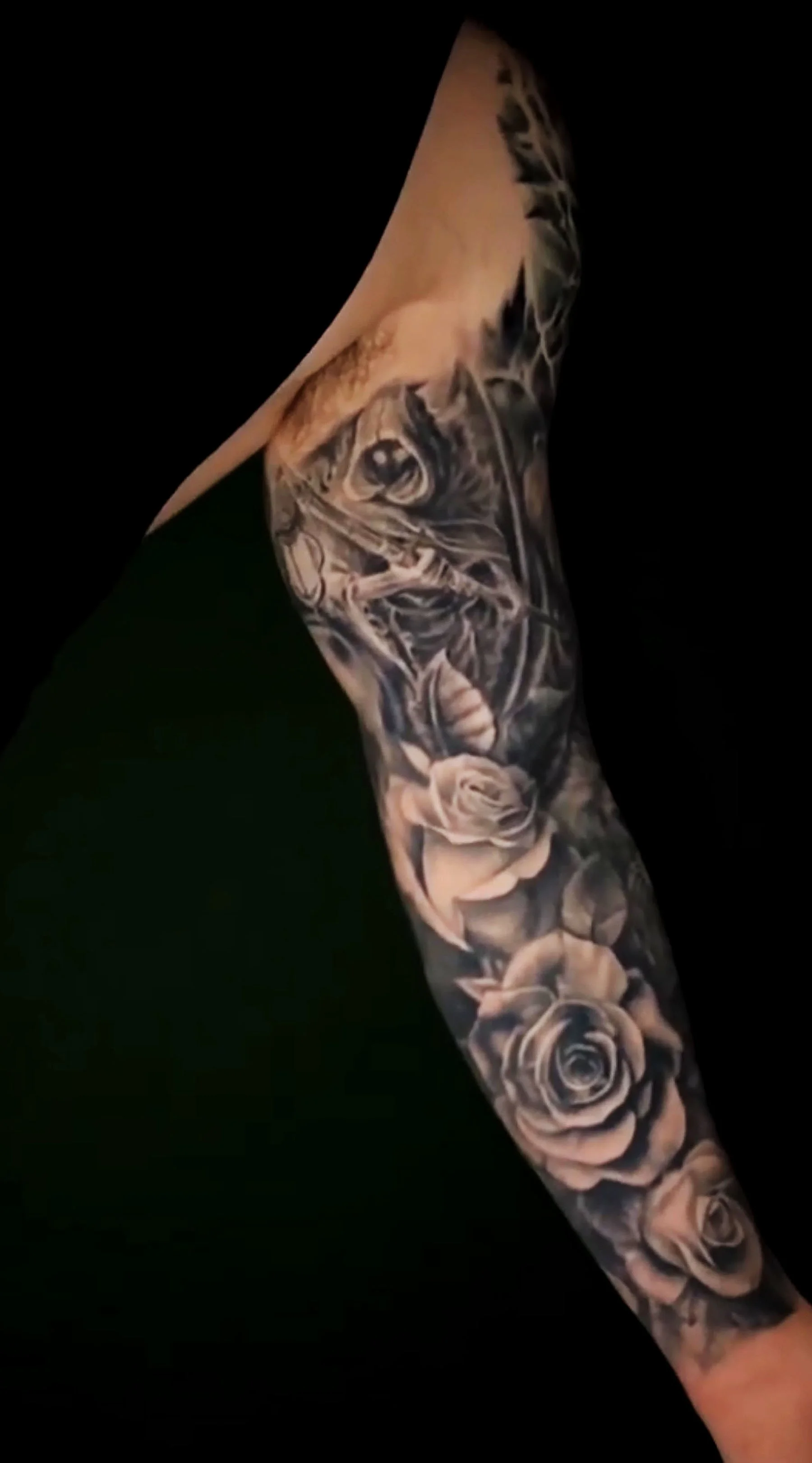 A tattoo sleeve featuring realistic black and gray roses covering the arm.