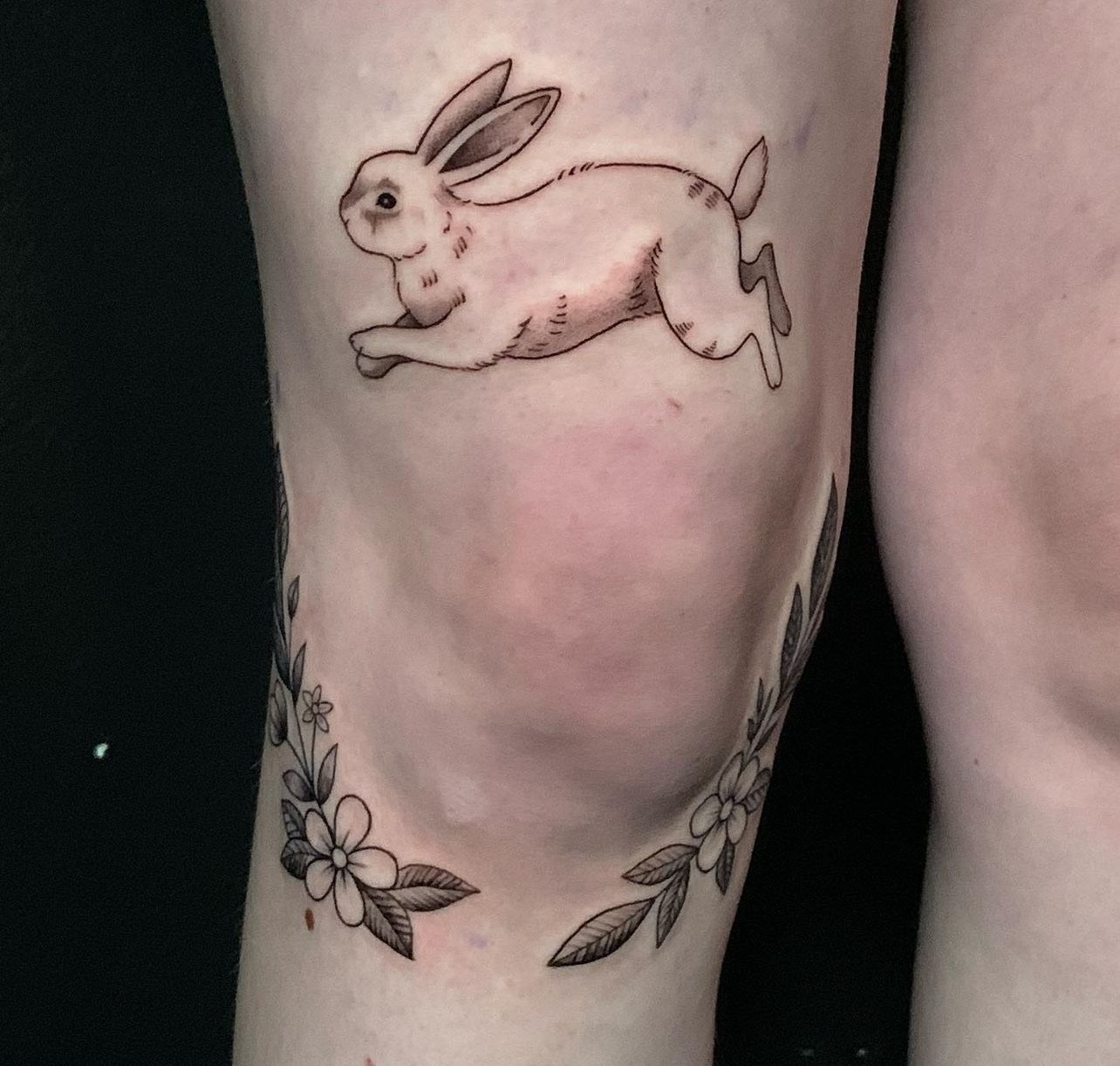 Tattoo of a cute rabbit with flowers on the arm.