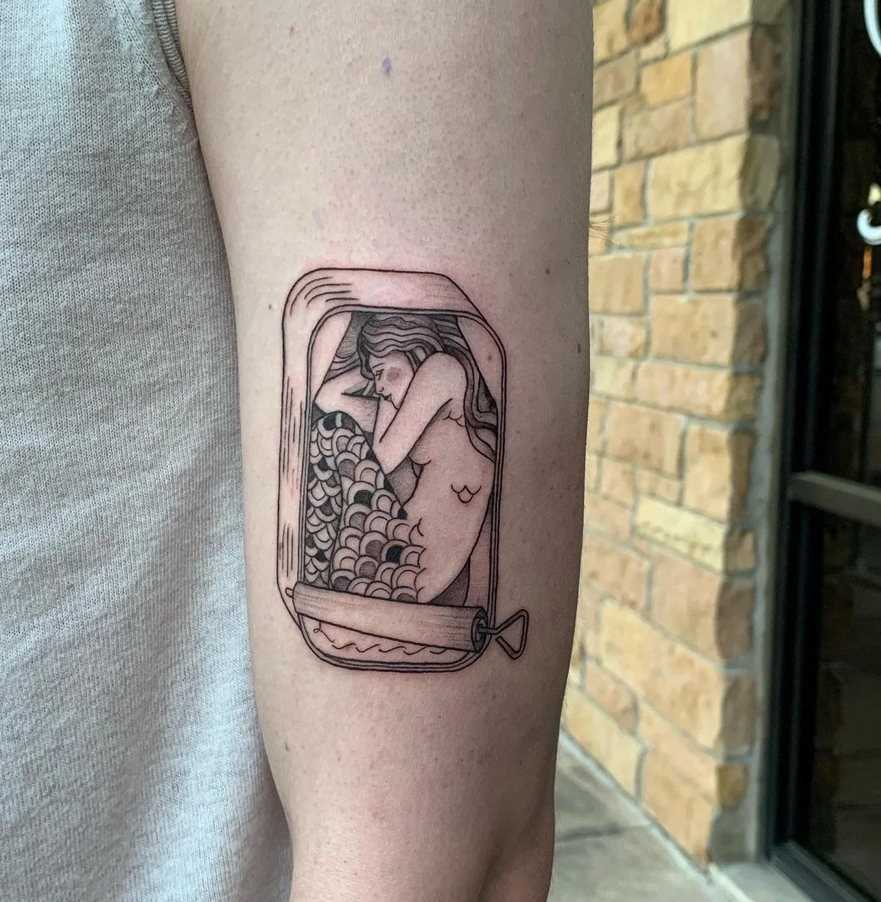 Tattoo of a woman sleeping inside a soda can, with bubbles and a straw, in minimalist black and gray line art style.