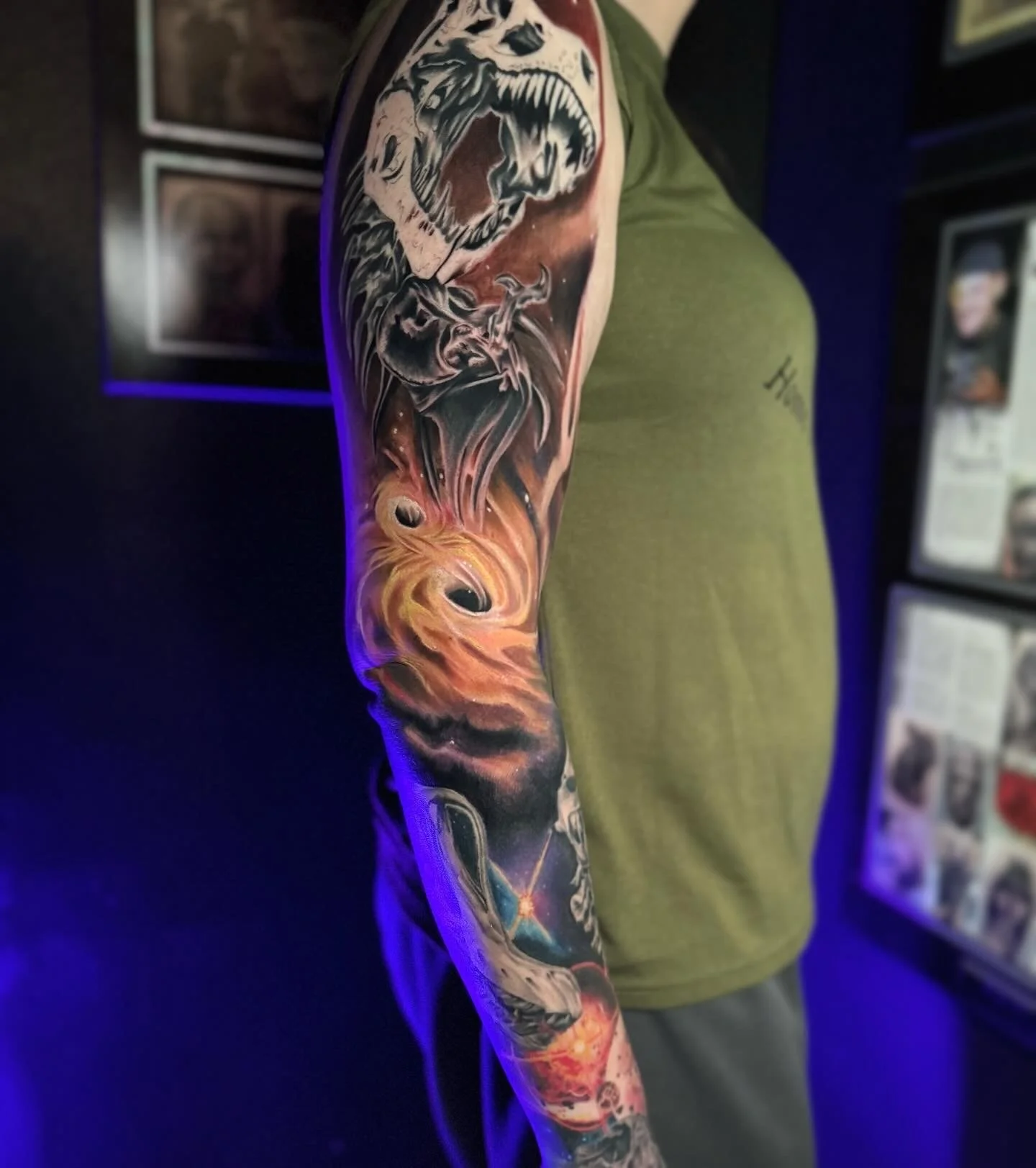Colorful full sleeve tattoo featuring a roaring bear, swirling flames, and cosmic elements on a person's arm.