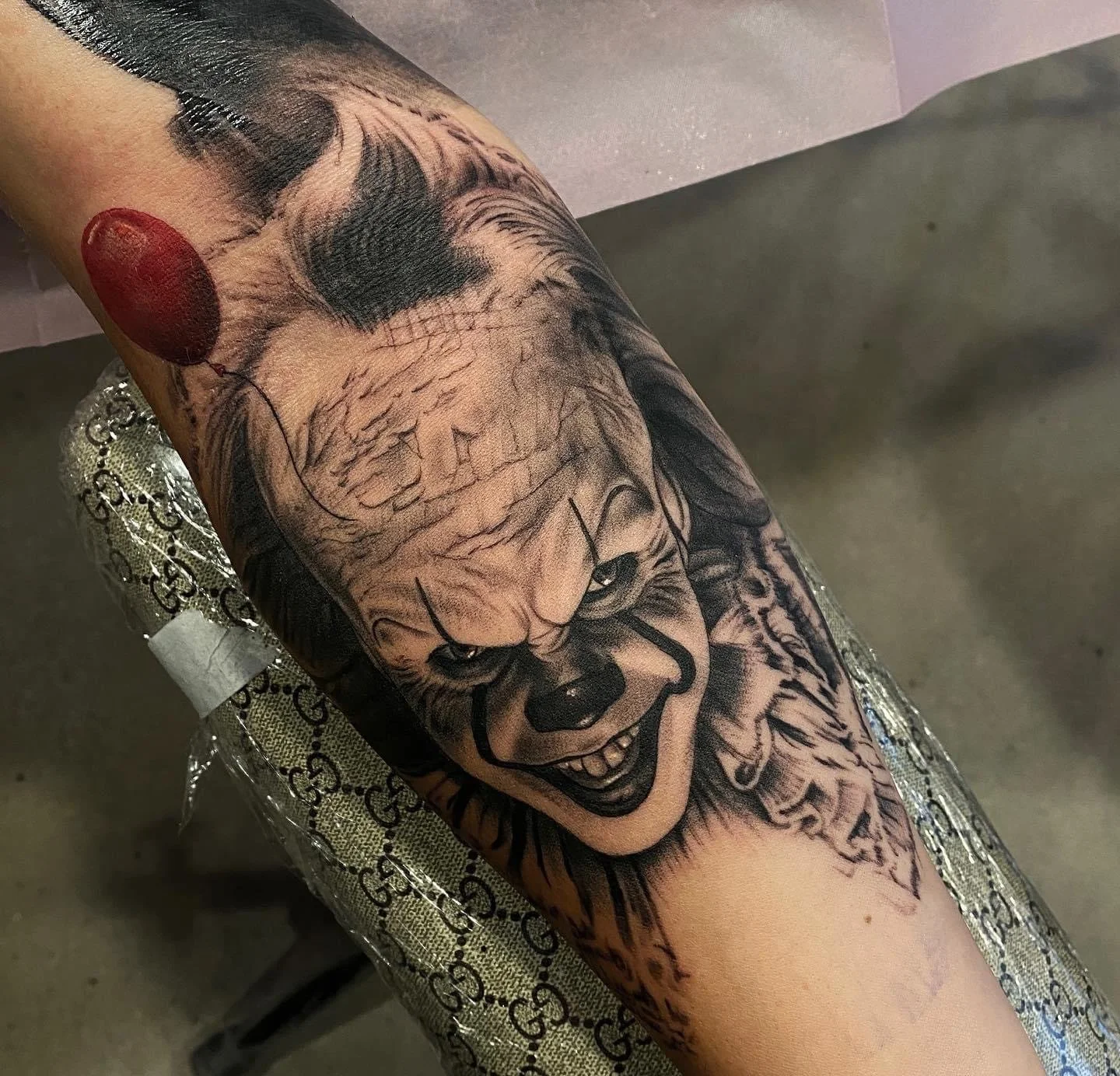 A tattoo on a person's arm features Pennywise the clown from Stephen King's 'It' with a red balloon.