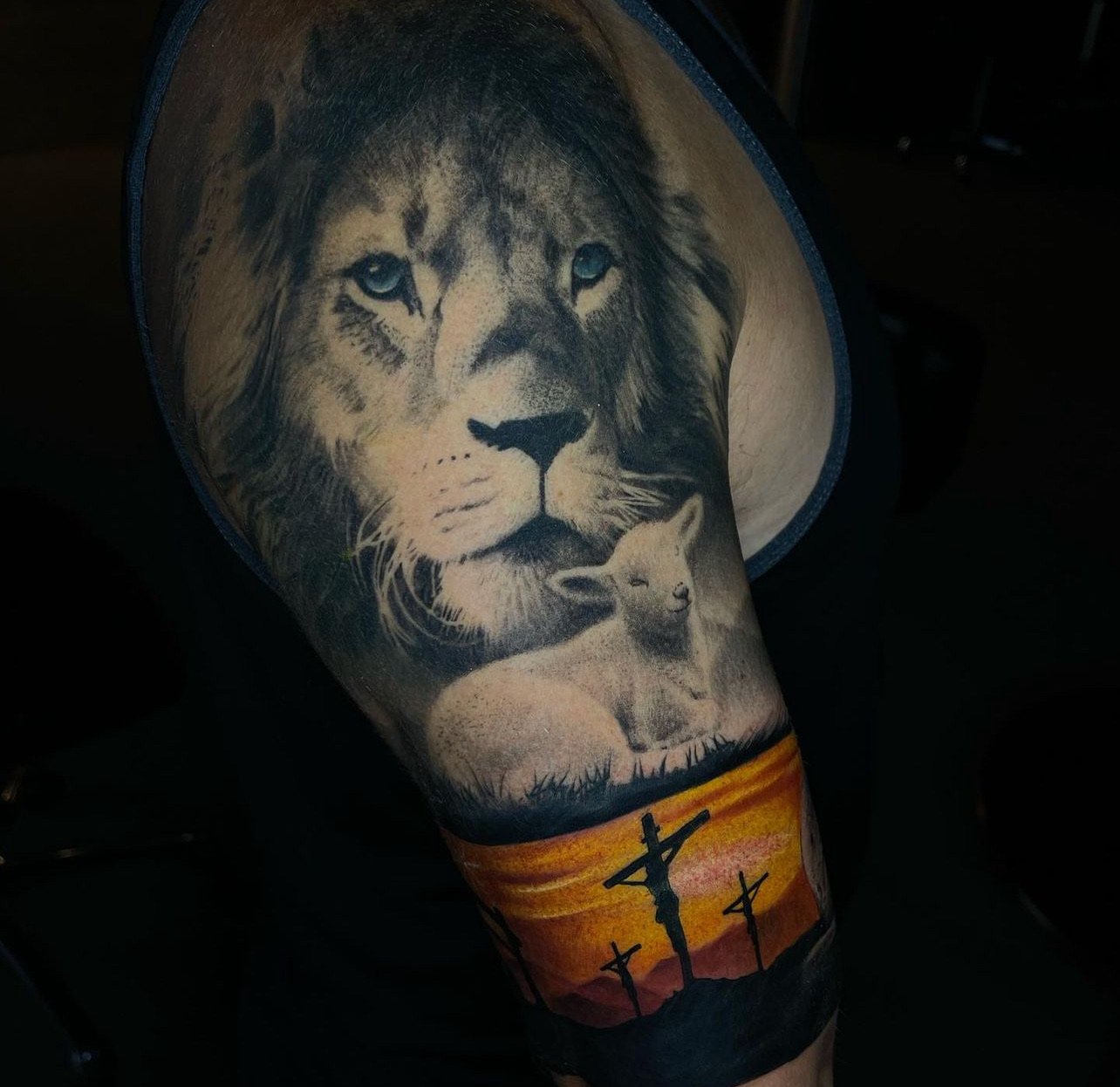 Tattoo of a lion's face and a lion cub, with a sunset and power lines in the background on a person's leg.