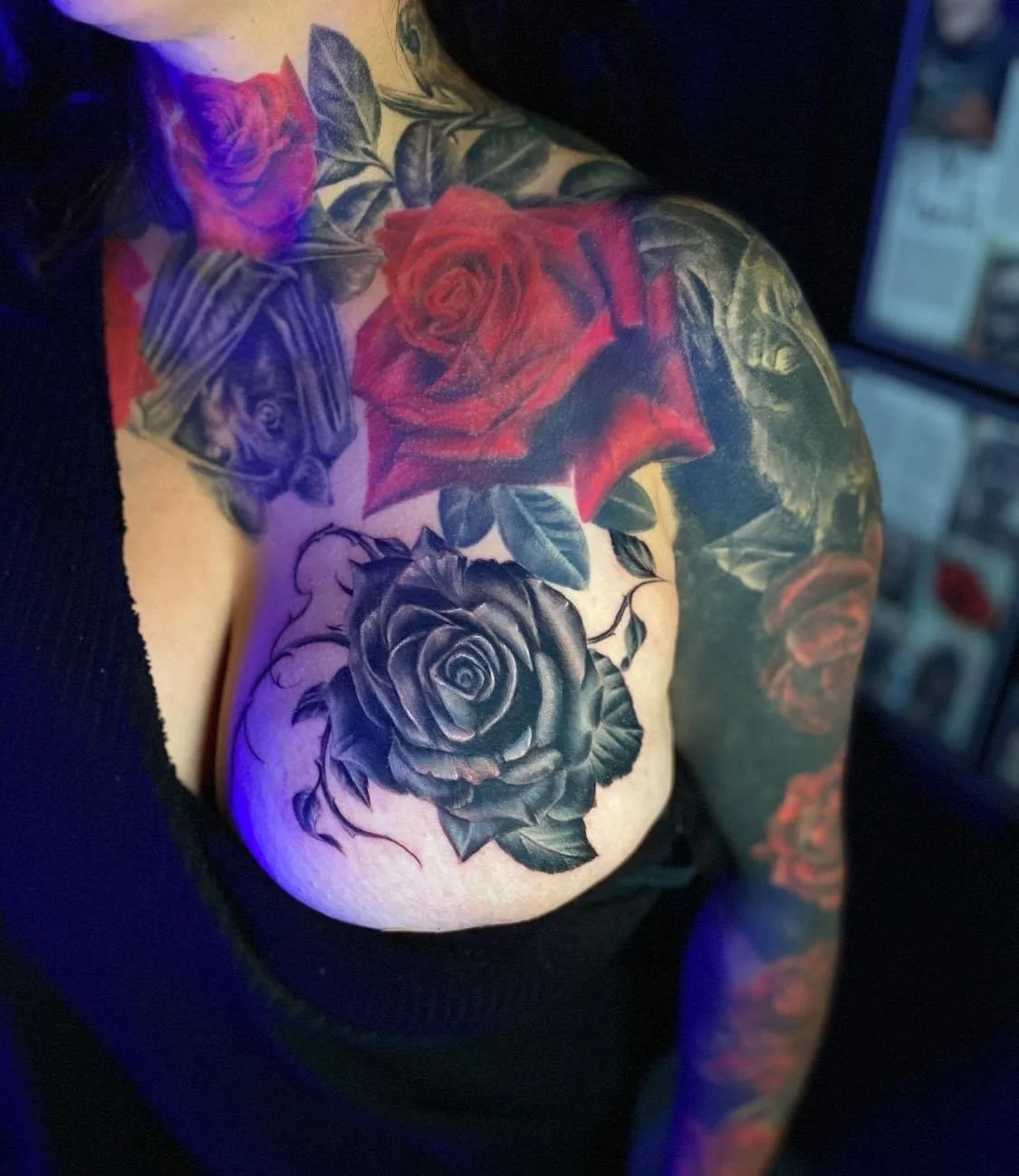 Tattoo of black and red roses on a person's shoulder and upper arm.