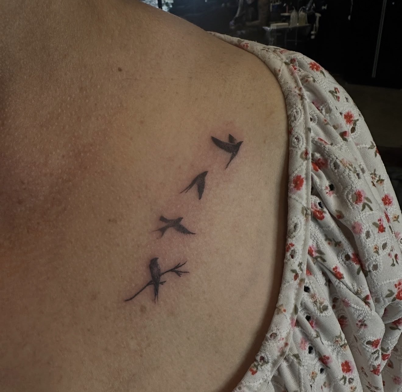 A tattoo of four black arrows pointing in different directions on a person's side, near their waist, with a floral patterned cloth partially covering their body.