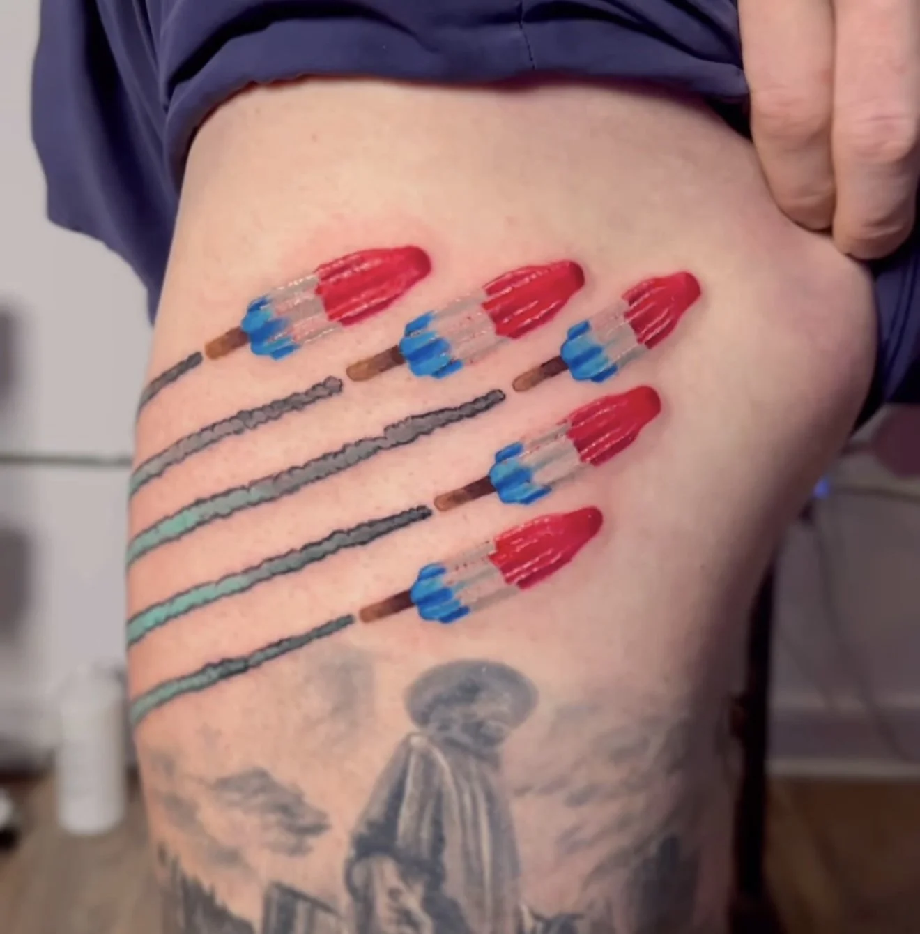 Tattoo of five syringes and a tattoo of an umbrella with a person walking beneath it.