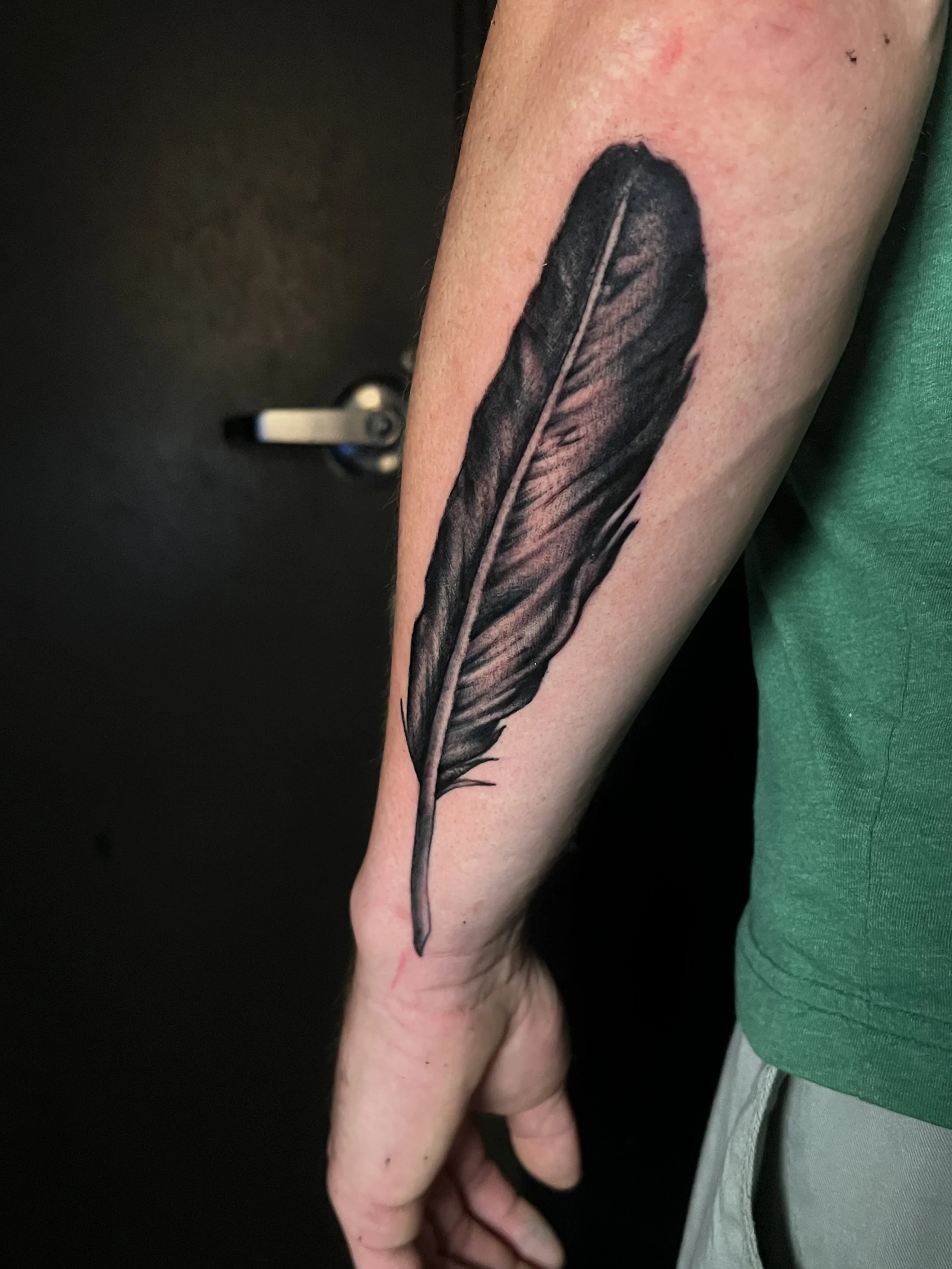 a black realistic tattoo on the outside of a person's forearm