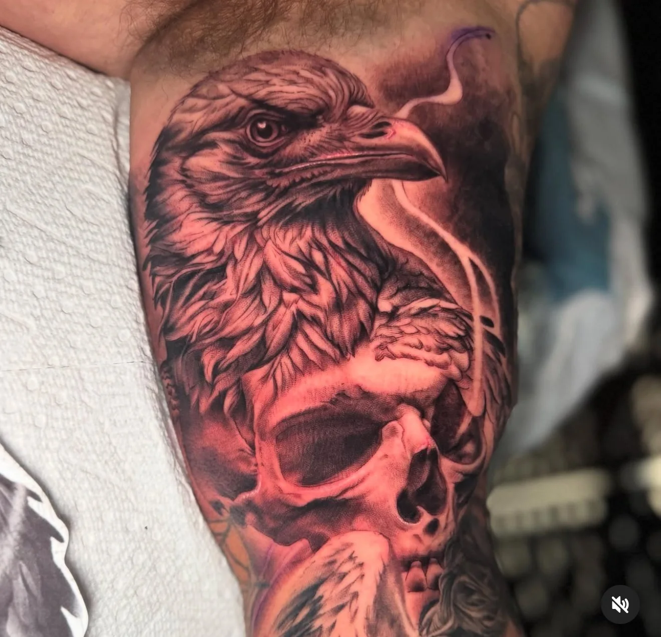 Black and gray realistic tattoo of an eagle's head and a skull on a person's arm.