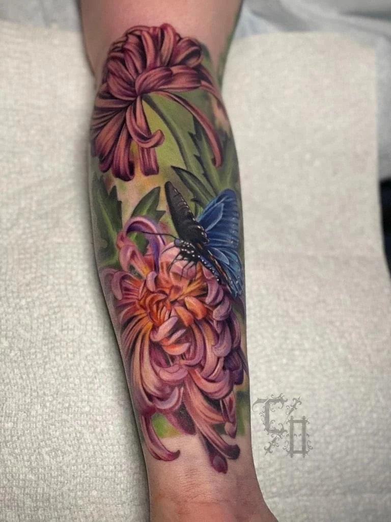 A colorful tattoo of pink and purple flowers with a blue and black butterfly on a person's arm.