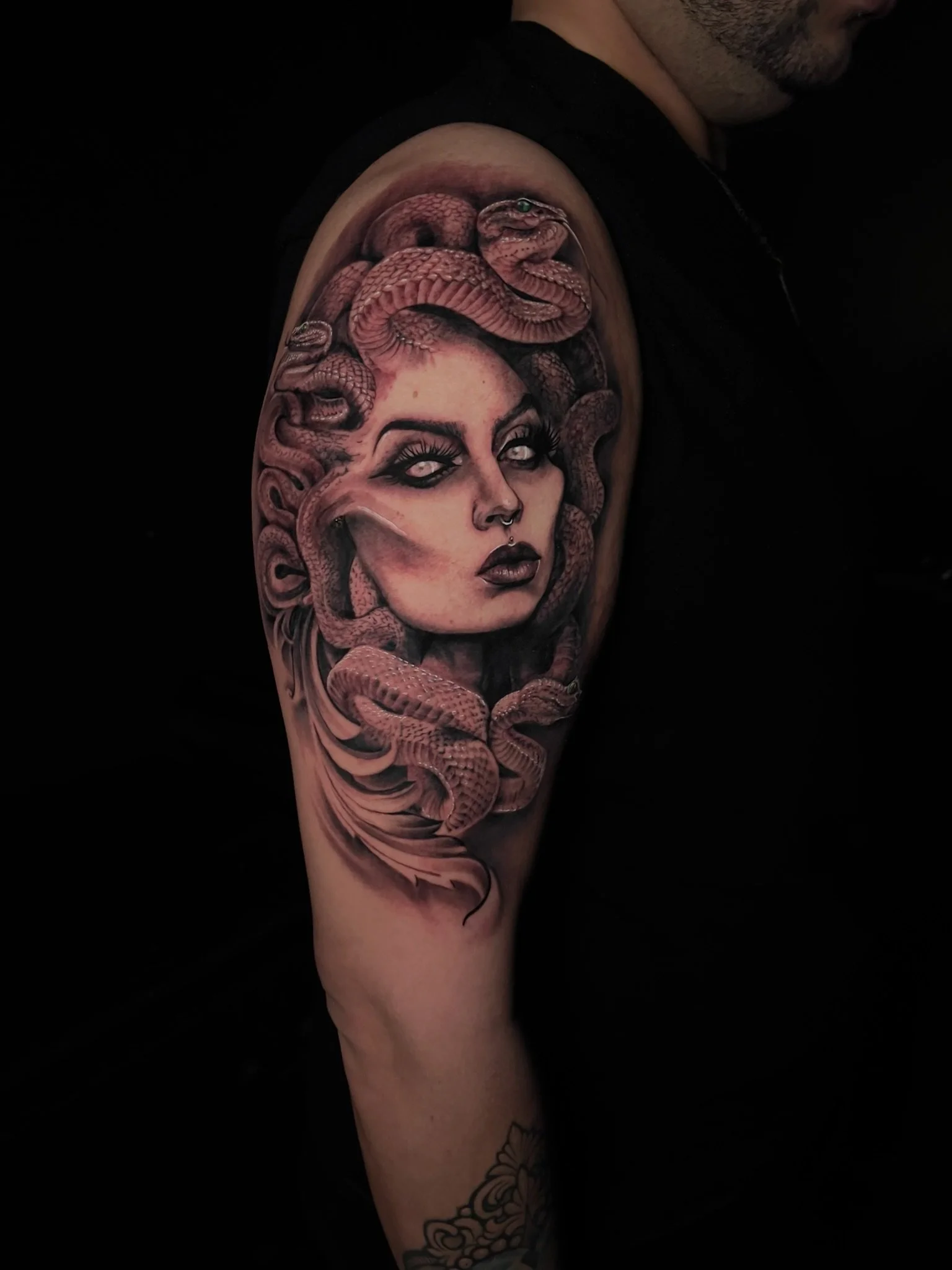 Tattoo of a woman with snakes surrounding her head on a person's upper arm.