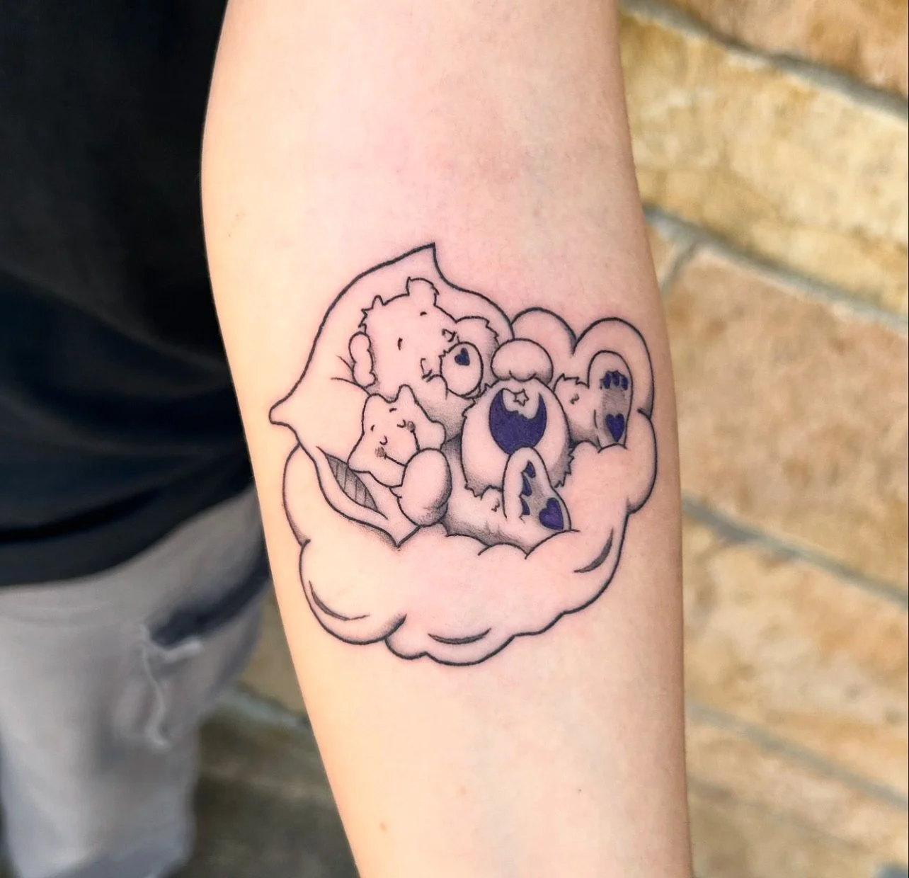 Tattoo of three cartoon bears cuddling on a cloud.