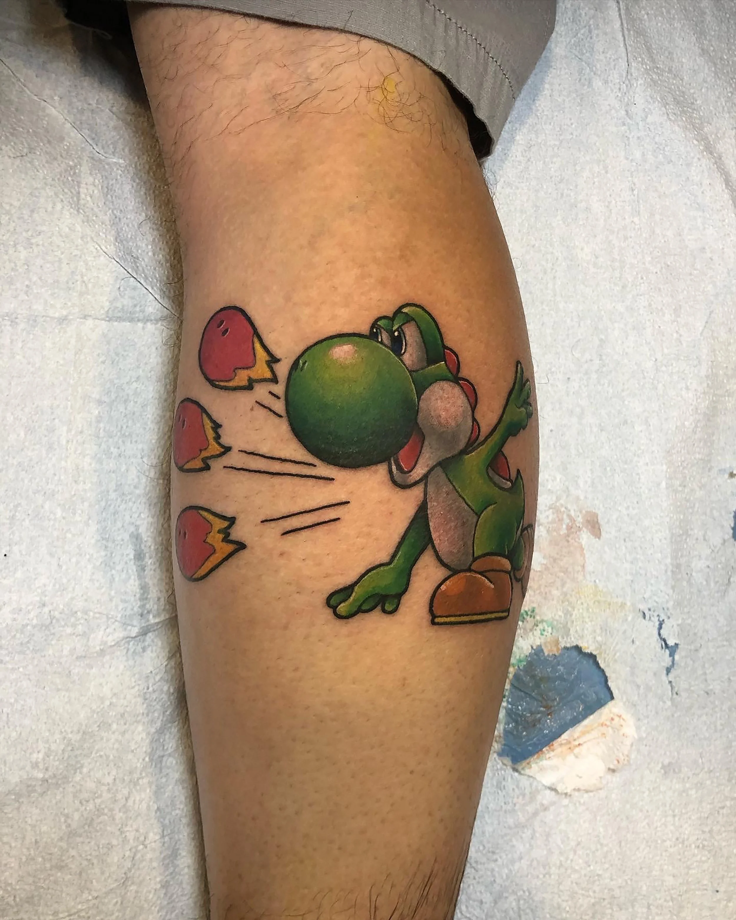colorful yoshi from the supermario bros franchise tattoo on somene's outer calf