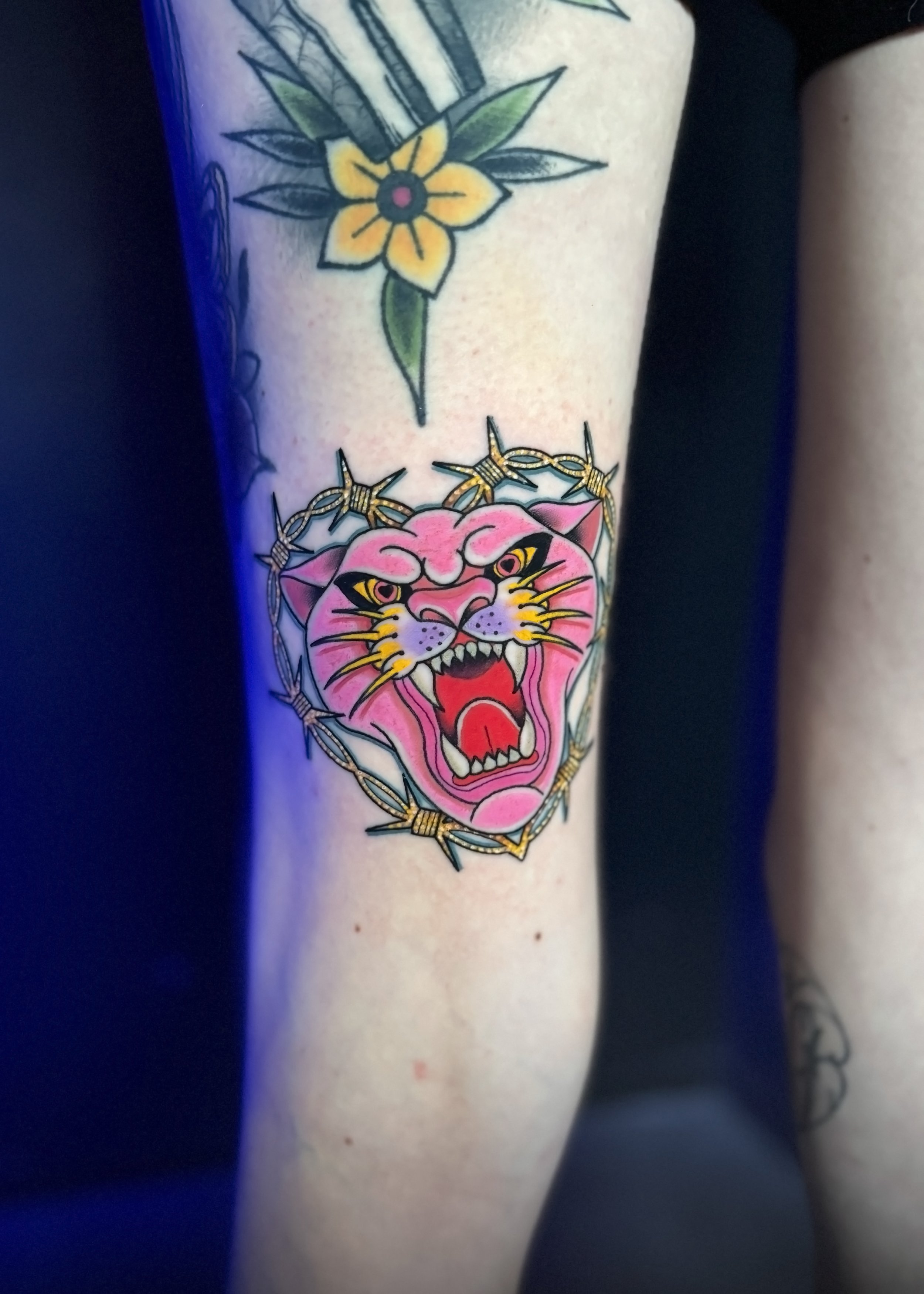 tattoo of a pink panther inside of barbed wire with heart eyes on the back of a person's thigh