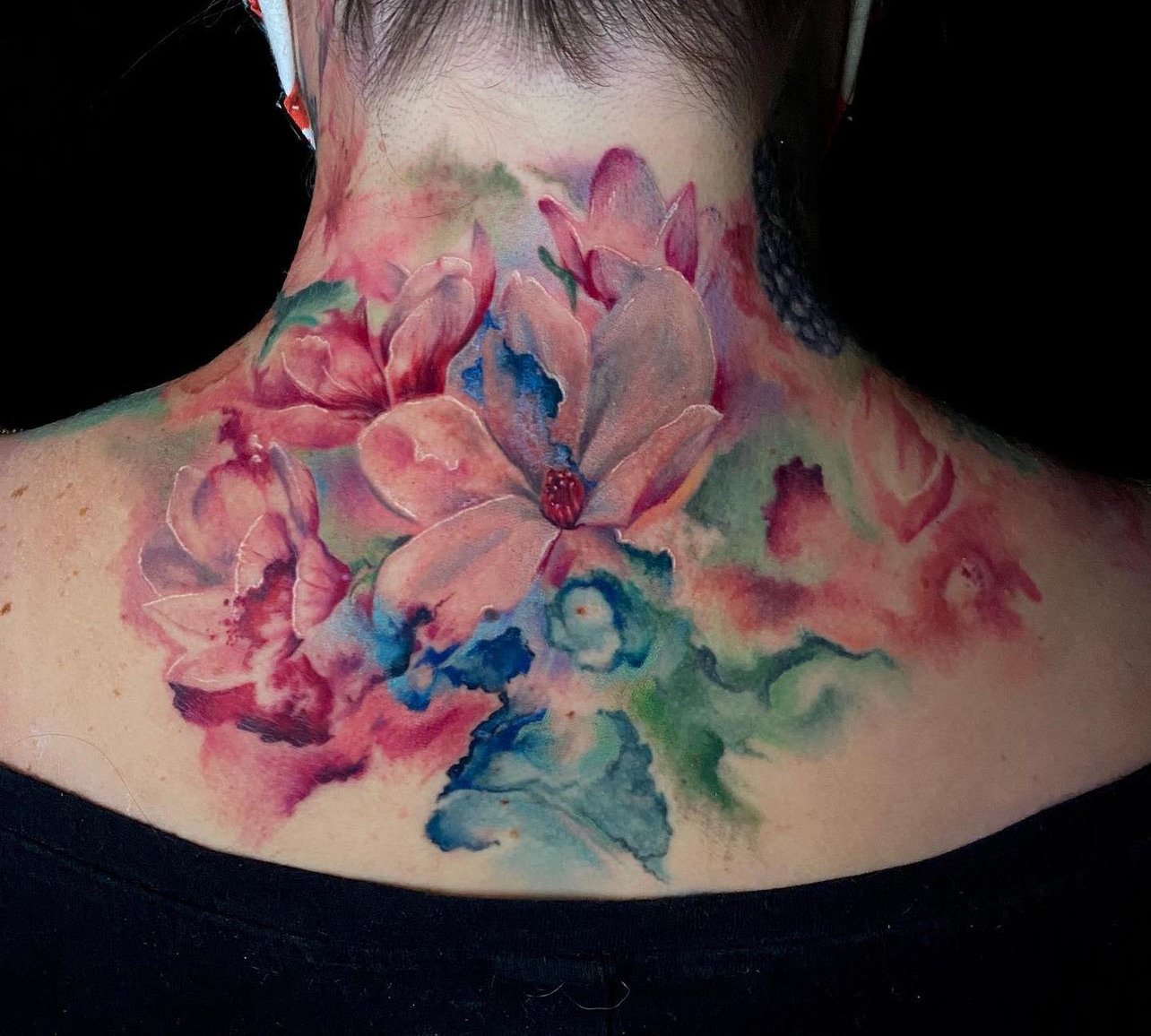 Colorful watercolor-style floral tattoo on neck featuring pink, blue, and green hues.