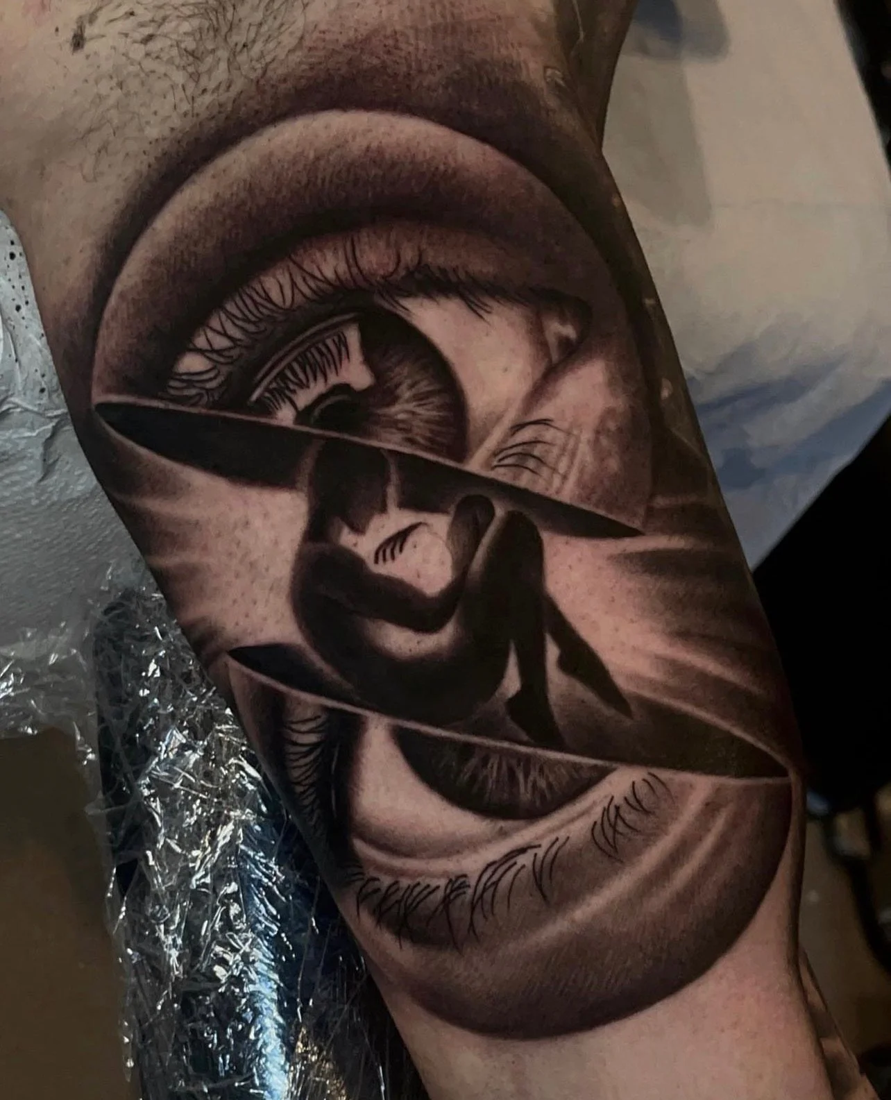 Tattoo of a realistic human eye and a silhouette of a person walking on a ledge inside the eye.