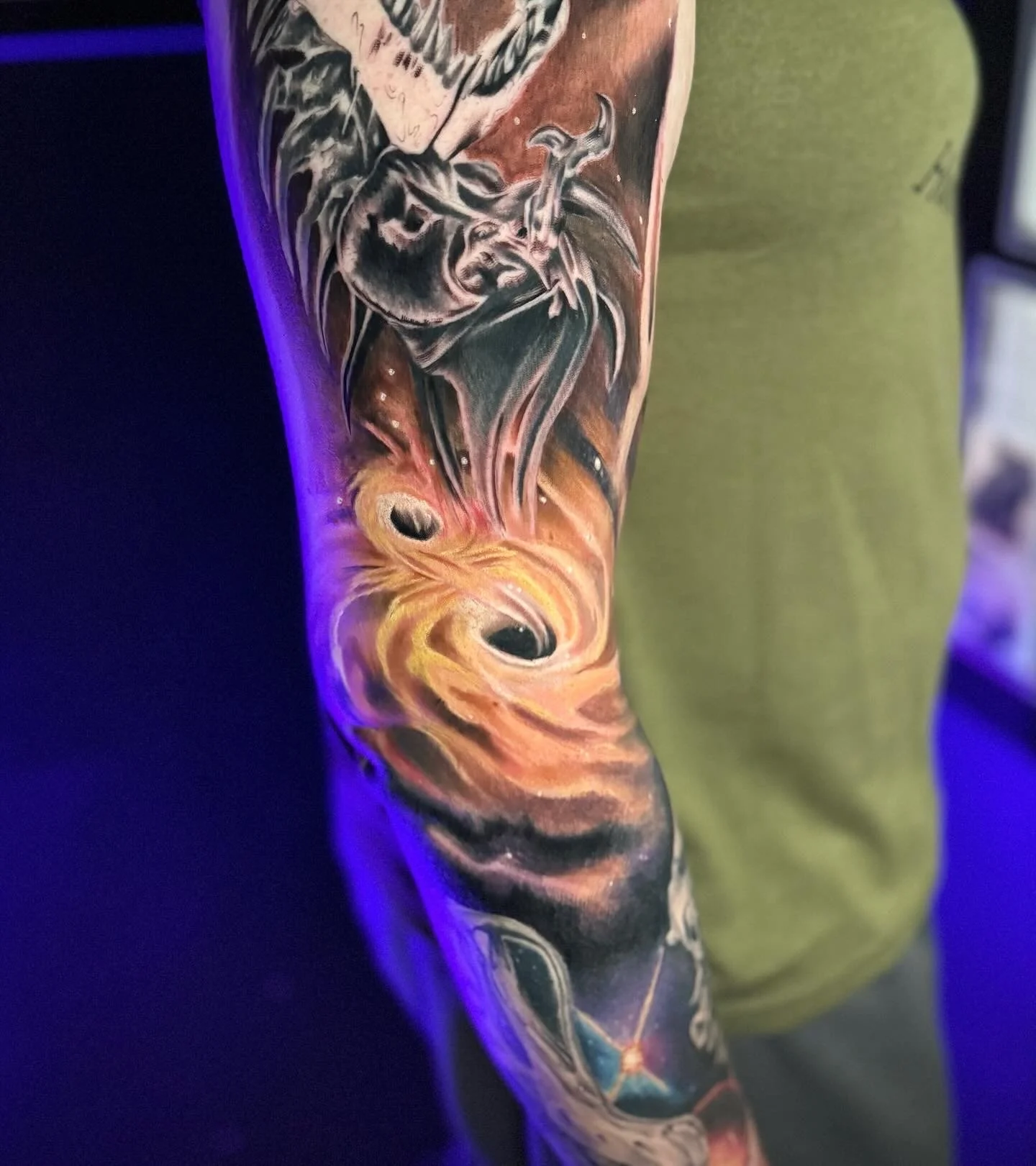 Close-up of a colorful tattoo sleeve featuring a skull, flames, and abstract design on a person's arm.