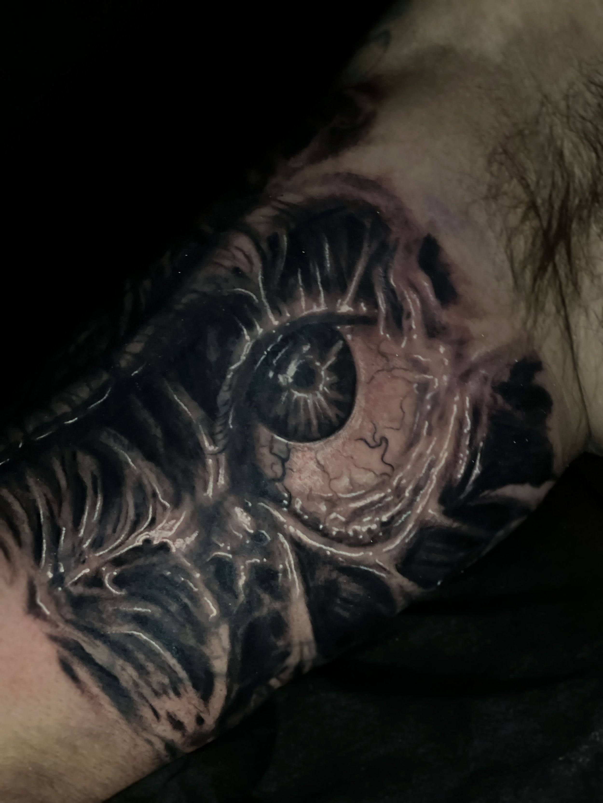 Close-up of a tattoo featuring a spiral design with black, white, and gray details on a person's skin.