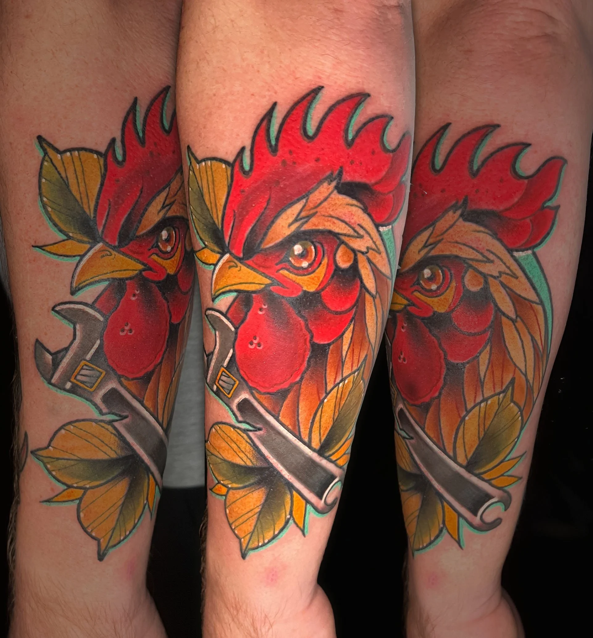 Colorful tattoo of a phoenix with red, yellow, and orange feathers, outlined in black, on a person's leg.