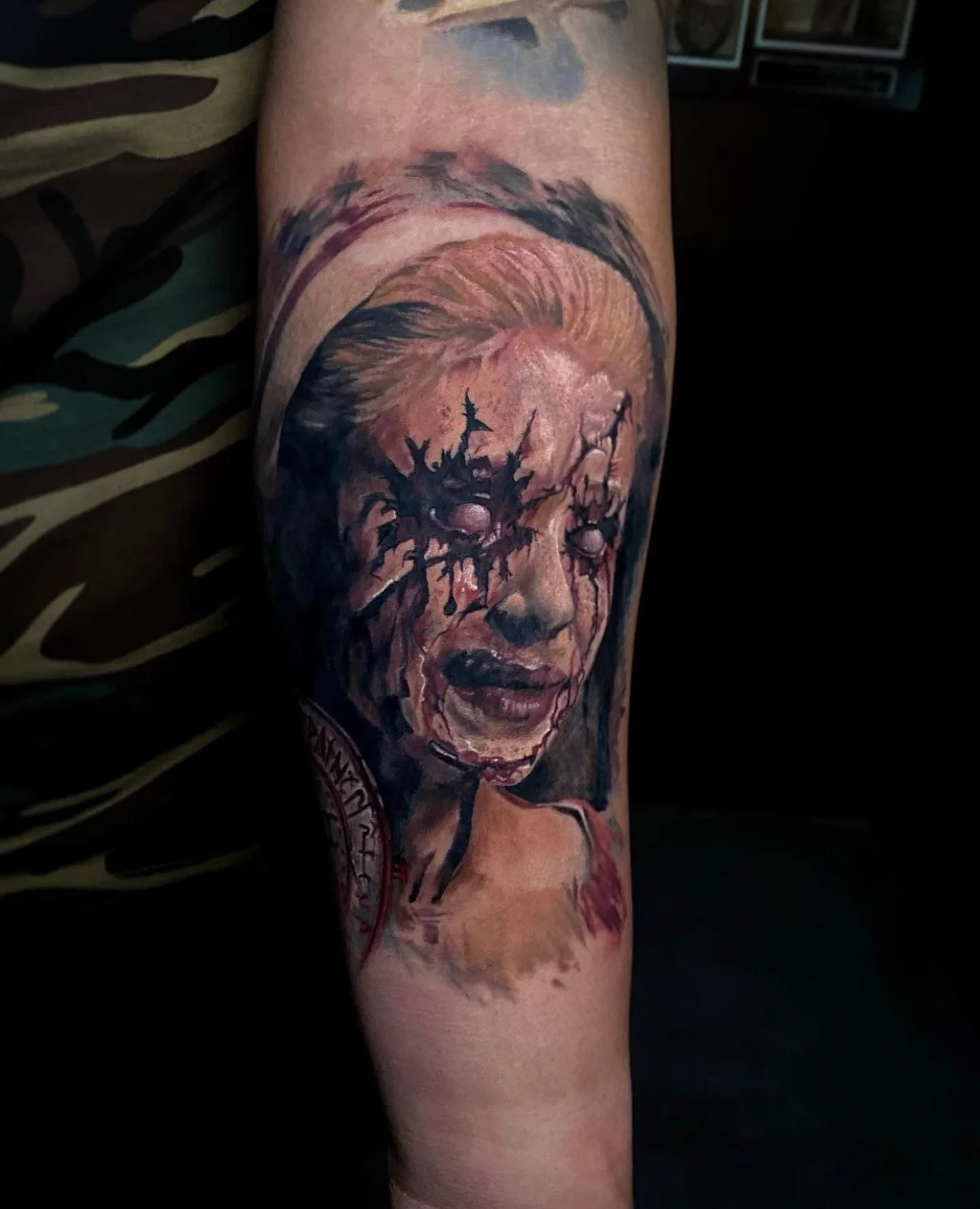 Tattoo of a woman’s face with painted makeup, crying with tears of blood, with a dark background.